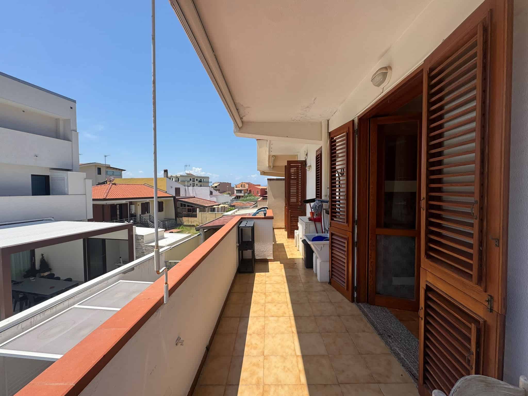 Balcone di una villa in vendita a Milazzo con vista sulla città e sul mare, con porte in legno e pavimento in ceramica.