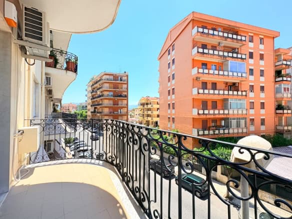 Balcone di un appartamento in vendita a Milazzo con vista su edifici moderni e il cielo azzurro.