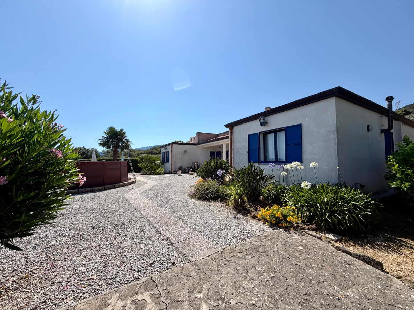Case vacanze con giardino e sentiero in pietra, vista soleggiata e cielo azzurro, ideale per soggiorni rilassanti a NextCasa.