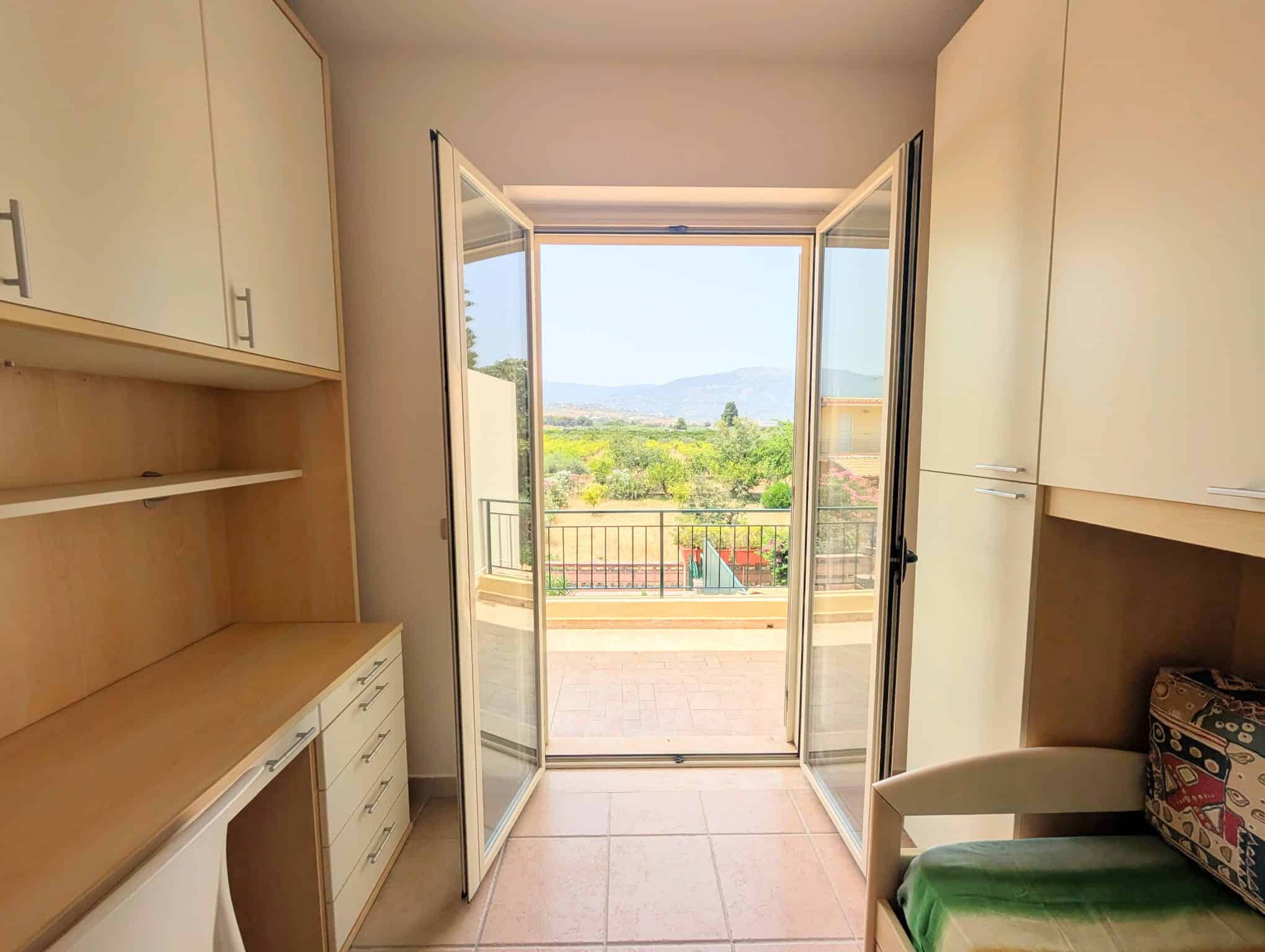Balcone con vista panoramica su campagna e montagne, accessibile da una porta finestra in una villetta a schiera.