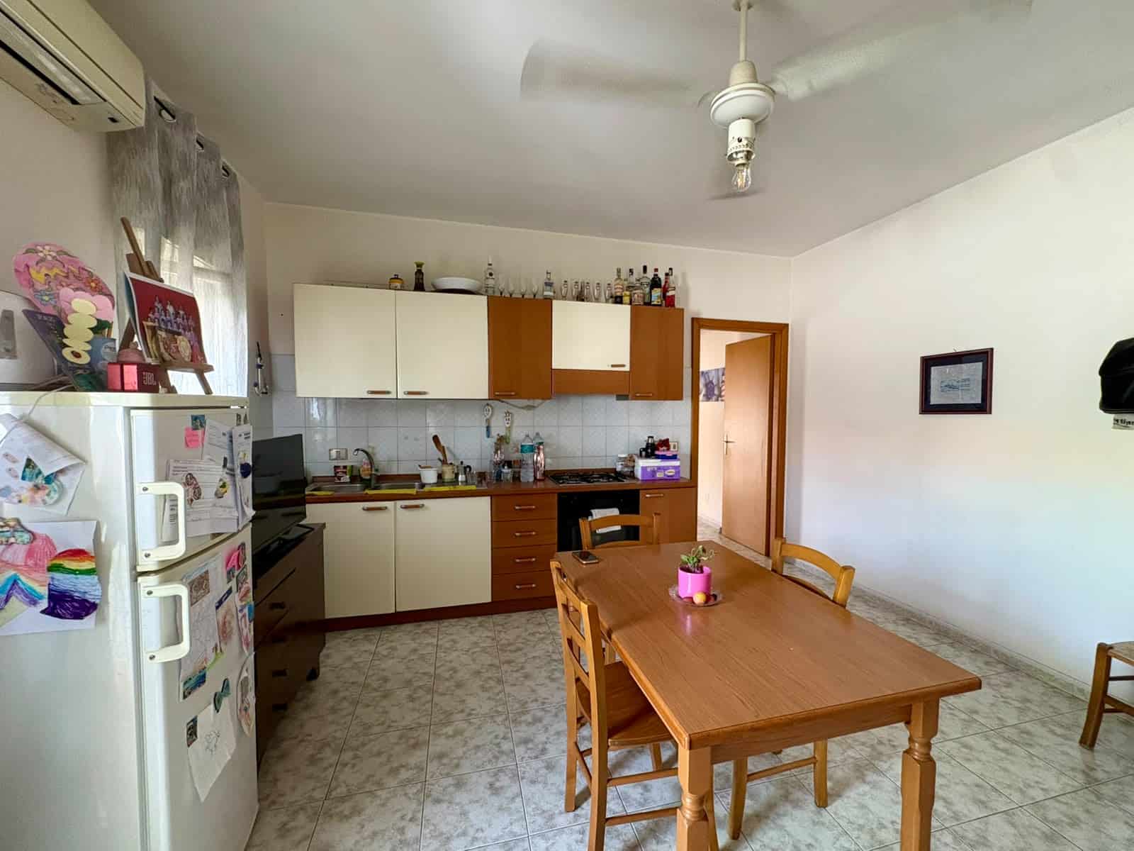 Interno di un appartamento con cucina e zona pranzo, arredato con mobili in legno e elettrodomestici.