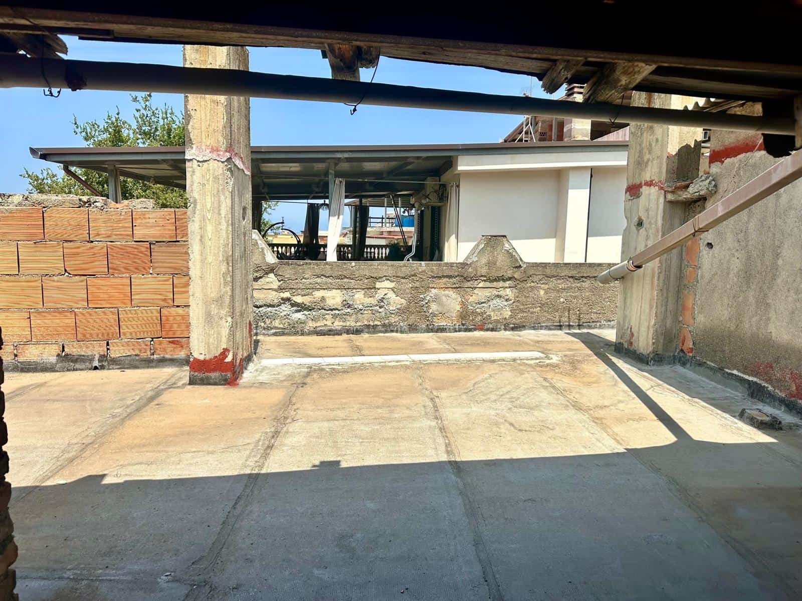 Spazio di un terrazzo in costruzione con pavimentazione e strutture in cemento e mattoni.