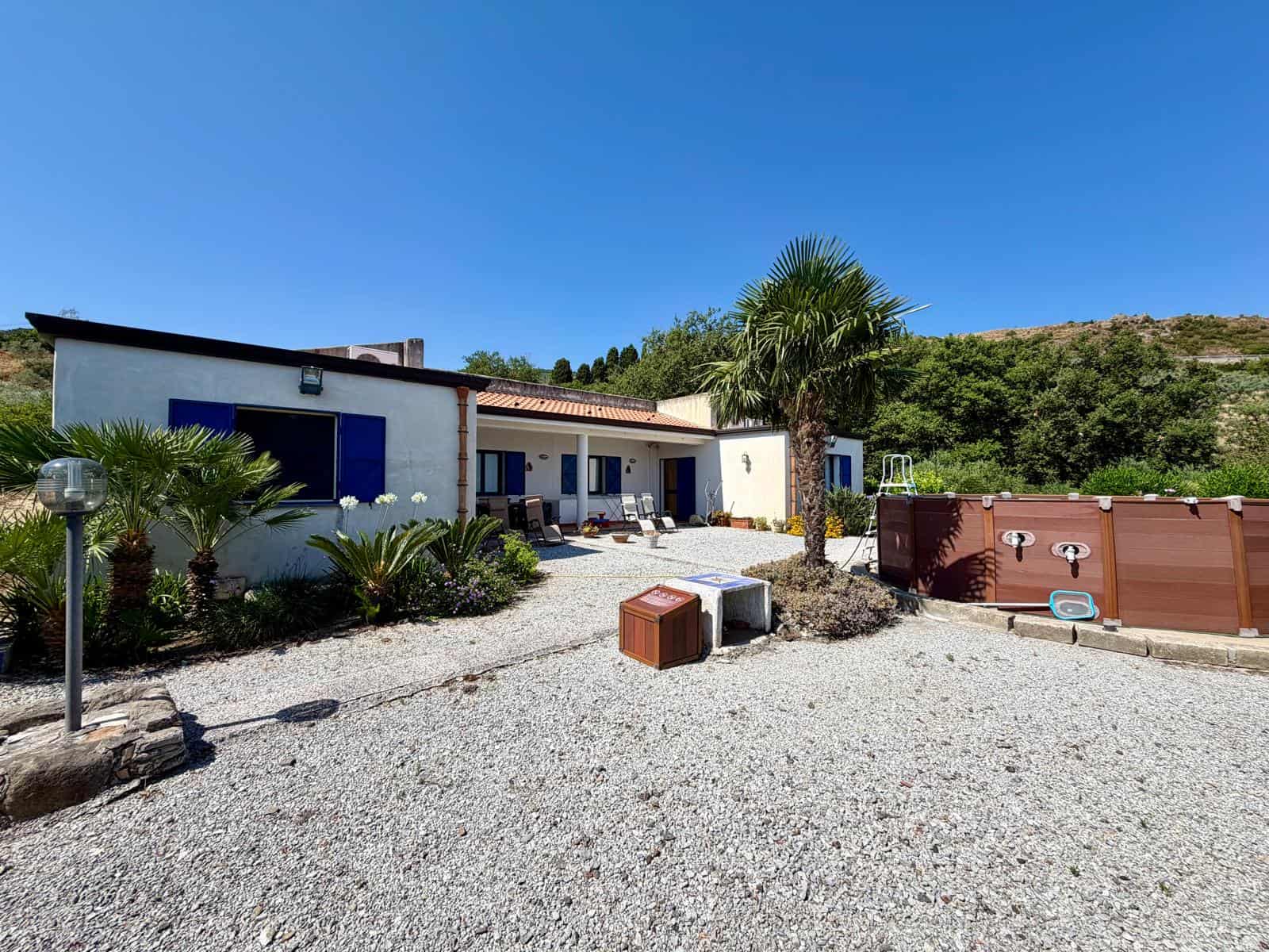 Casa moderna con giardino e piscina all'aperto, vista panoramica sulle colline, ambiente esterno soleggiato e accogliente.