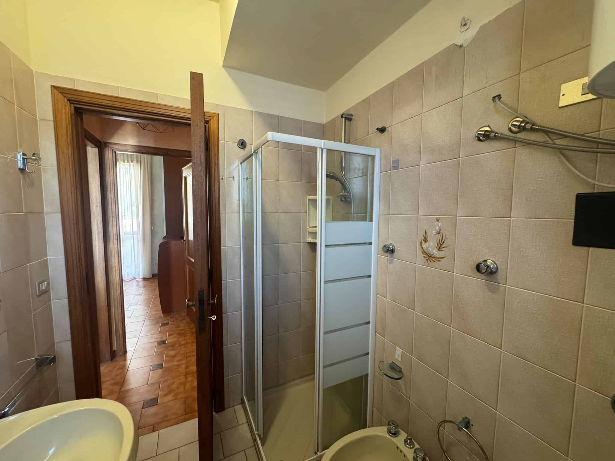 Interno bagno con doccia, piastrelle beige e accessori moderni, in una villa in vendita a Milazzo.