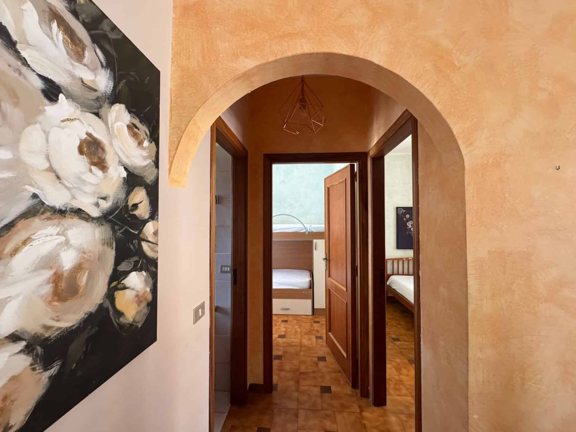 Vista degli interni di una villa in vendita a Milazzo, con camere da letto e arredi moderni, visibile attraverso un arco in pietra.