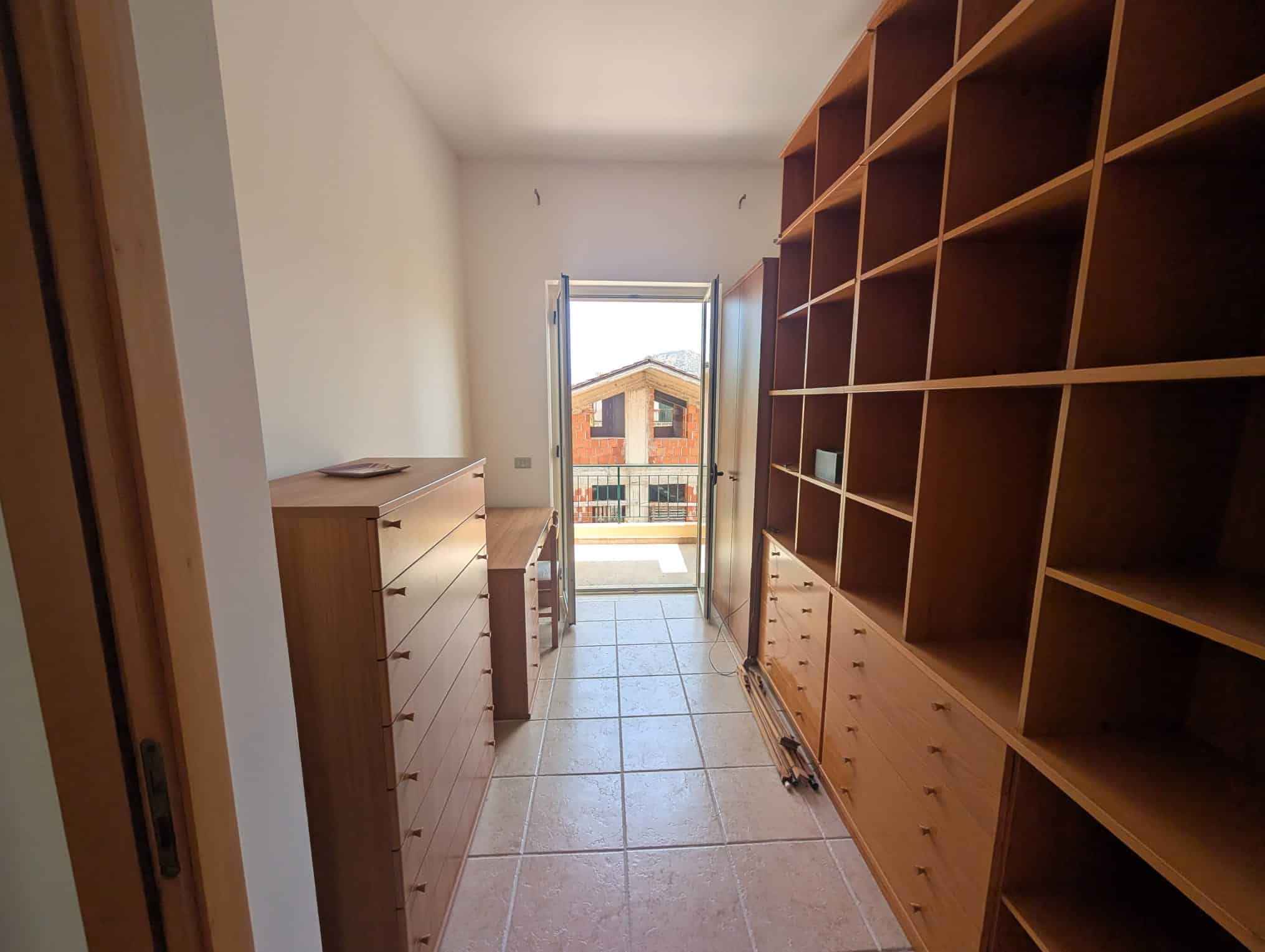 Interno di una villetta a schiera con armadiature in legno e porta finestra che dà su un balcone.