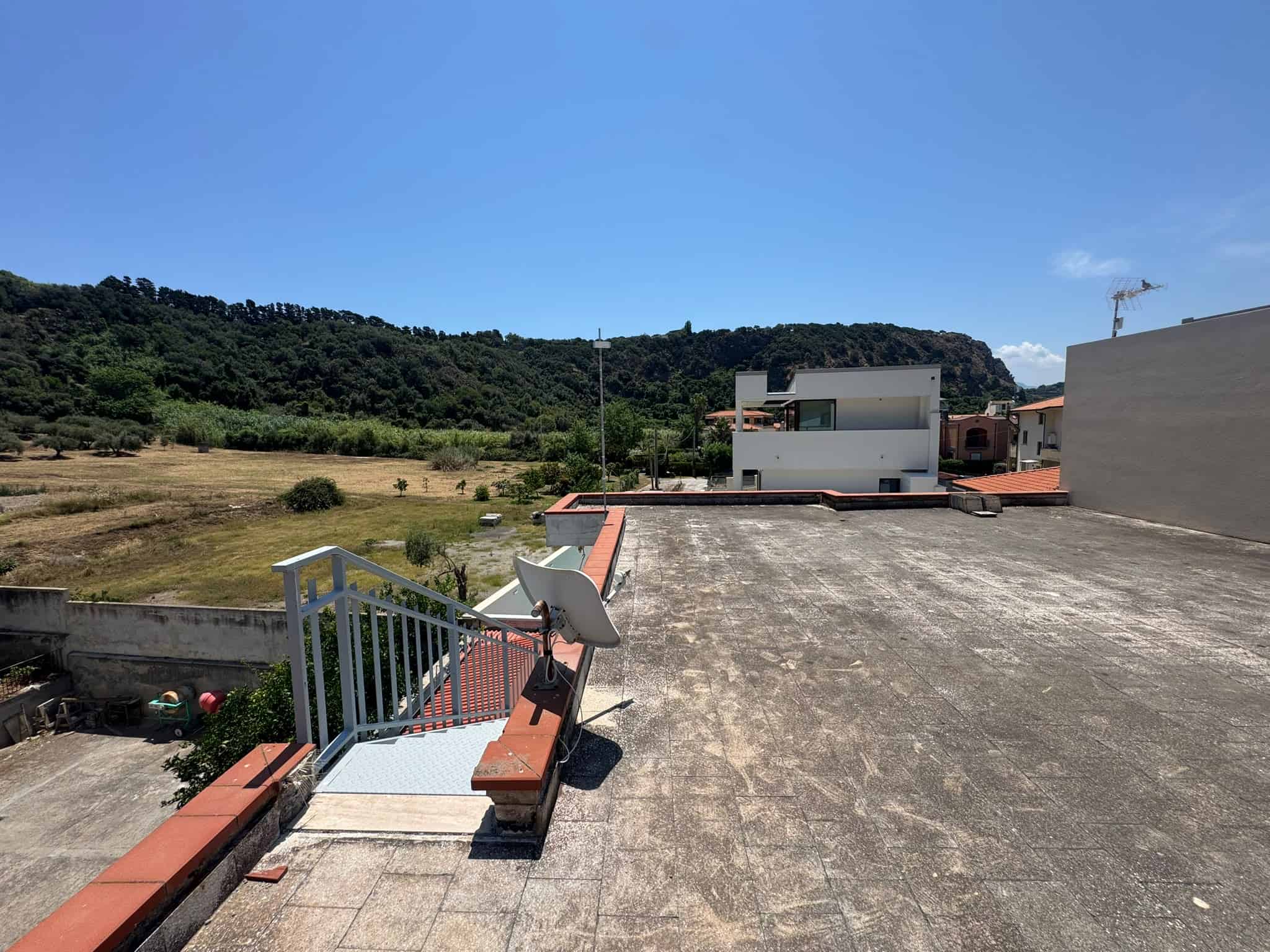 Terrazza panoramica con vista su campagna, colline e cielo azzurro, ideale per relax e momenti all'aperto.