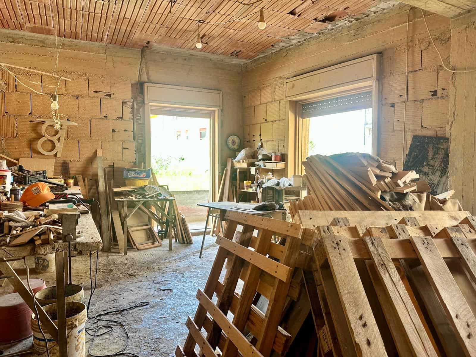Interno di una casa in costruzione con materiali e attrezzi da lavoro disposti ovunque.