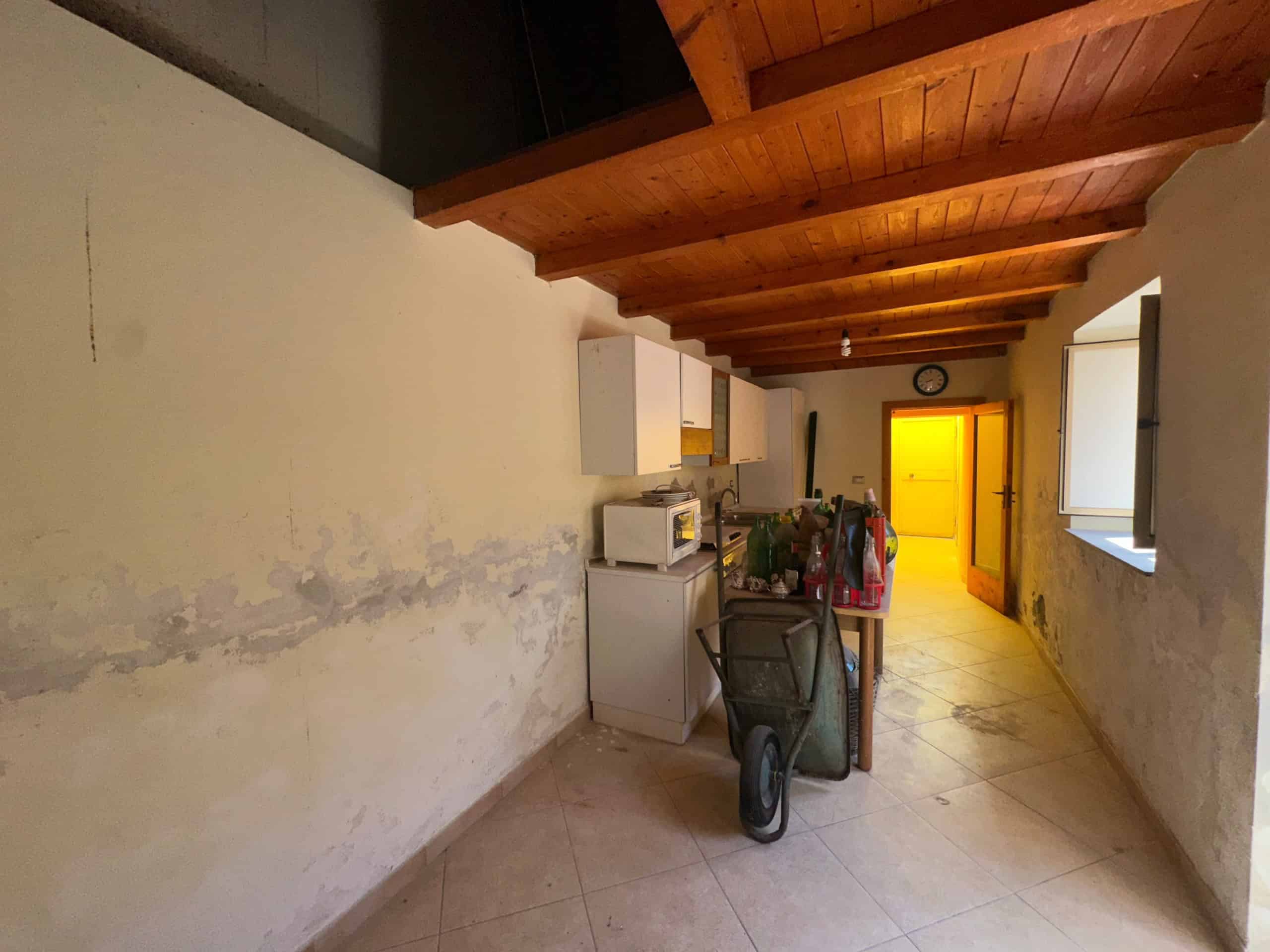 Interno di una casa indipendente in vendita a Milazzo con soffitto in legno e pareti con segni di umidità.