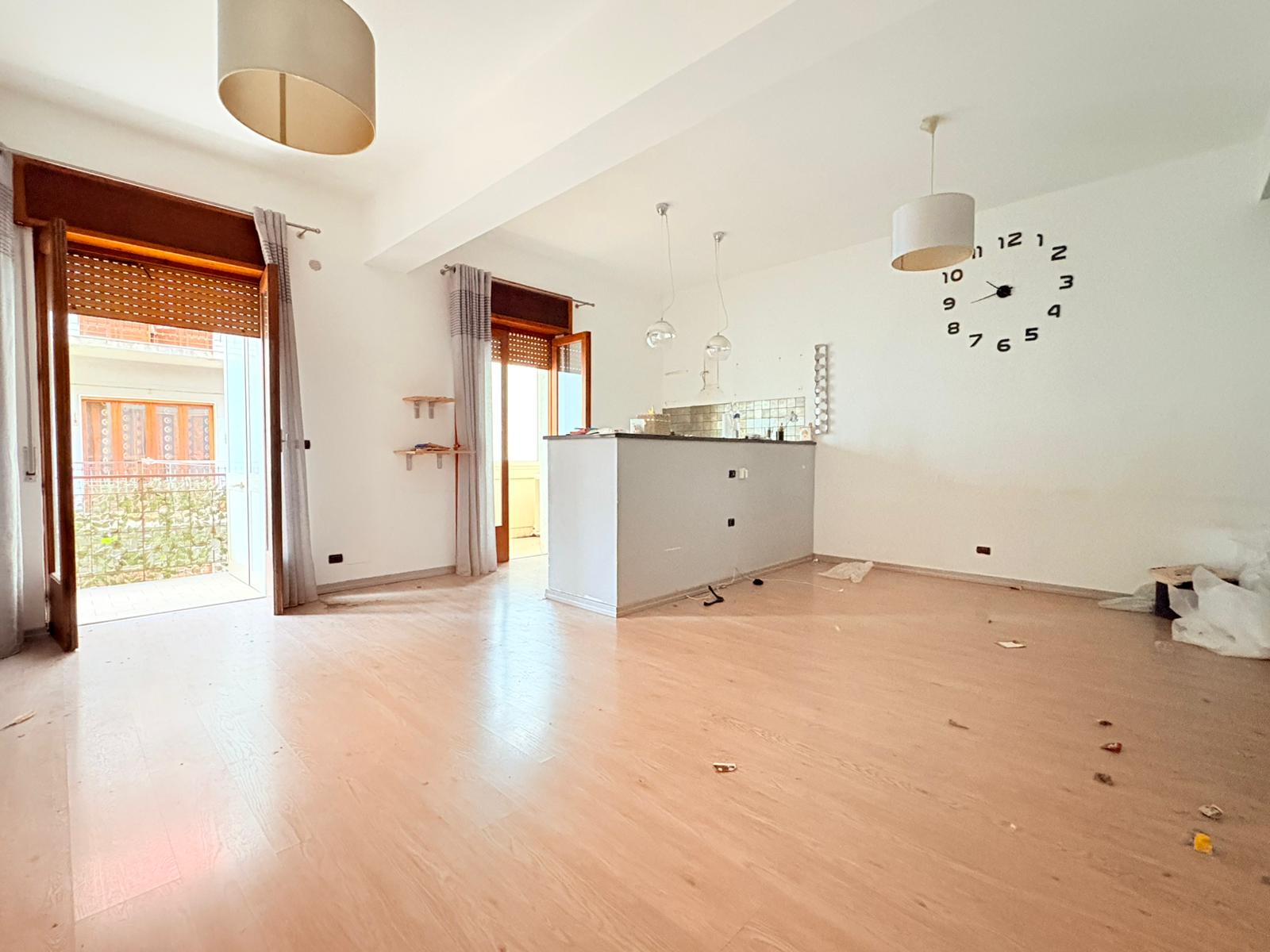 Interno luminoso di un appartamento in affitto a Milazzo con pareti bianche e pavimento in legno chiaro.