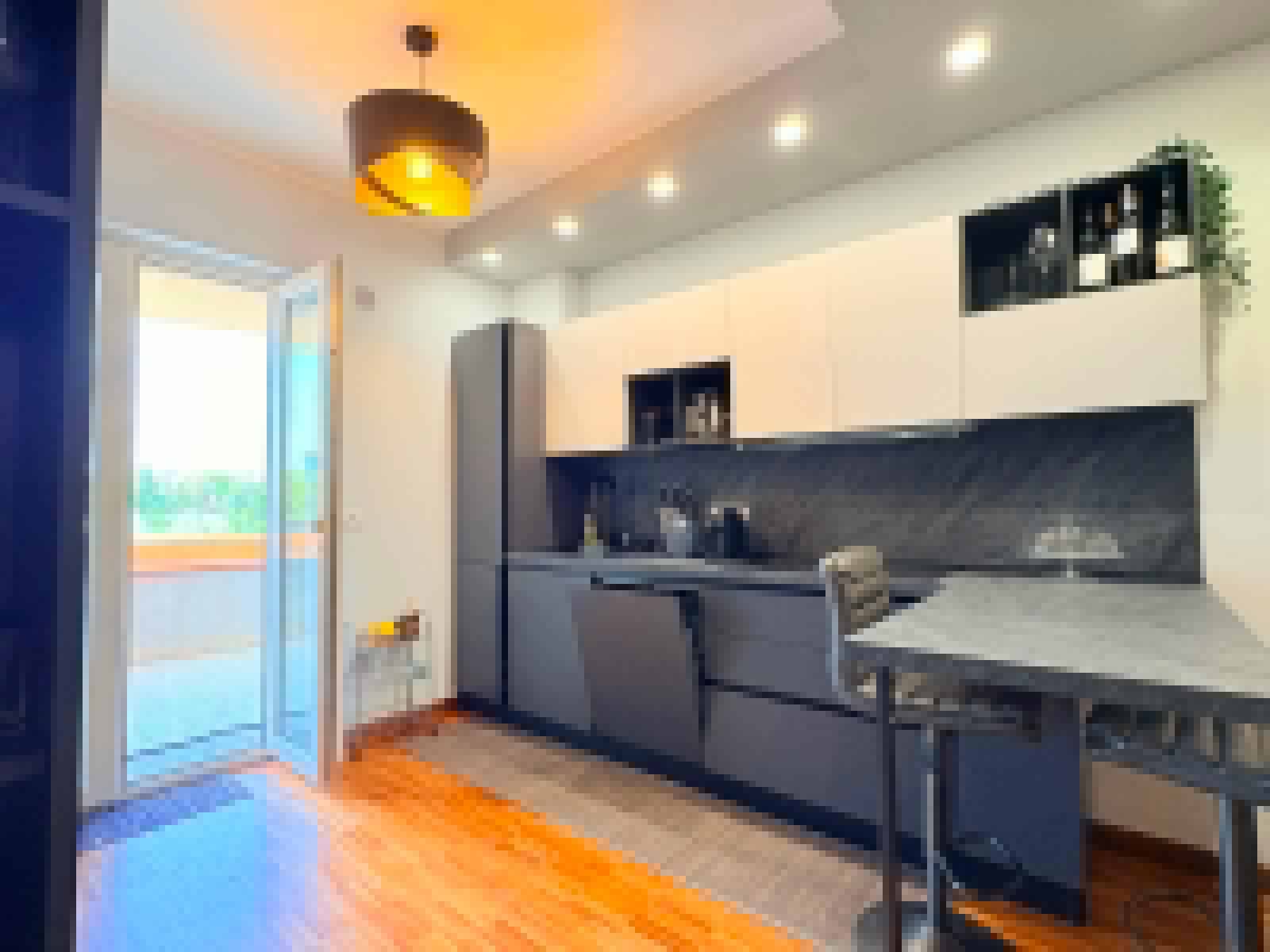 Cucina moderna con mobili bianchi e grigi, balcone con vista luminosa, illuminazione a soffitto, ideale per appartamento in vendita a Milazzo.