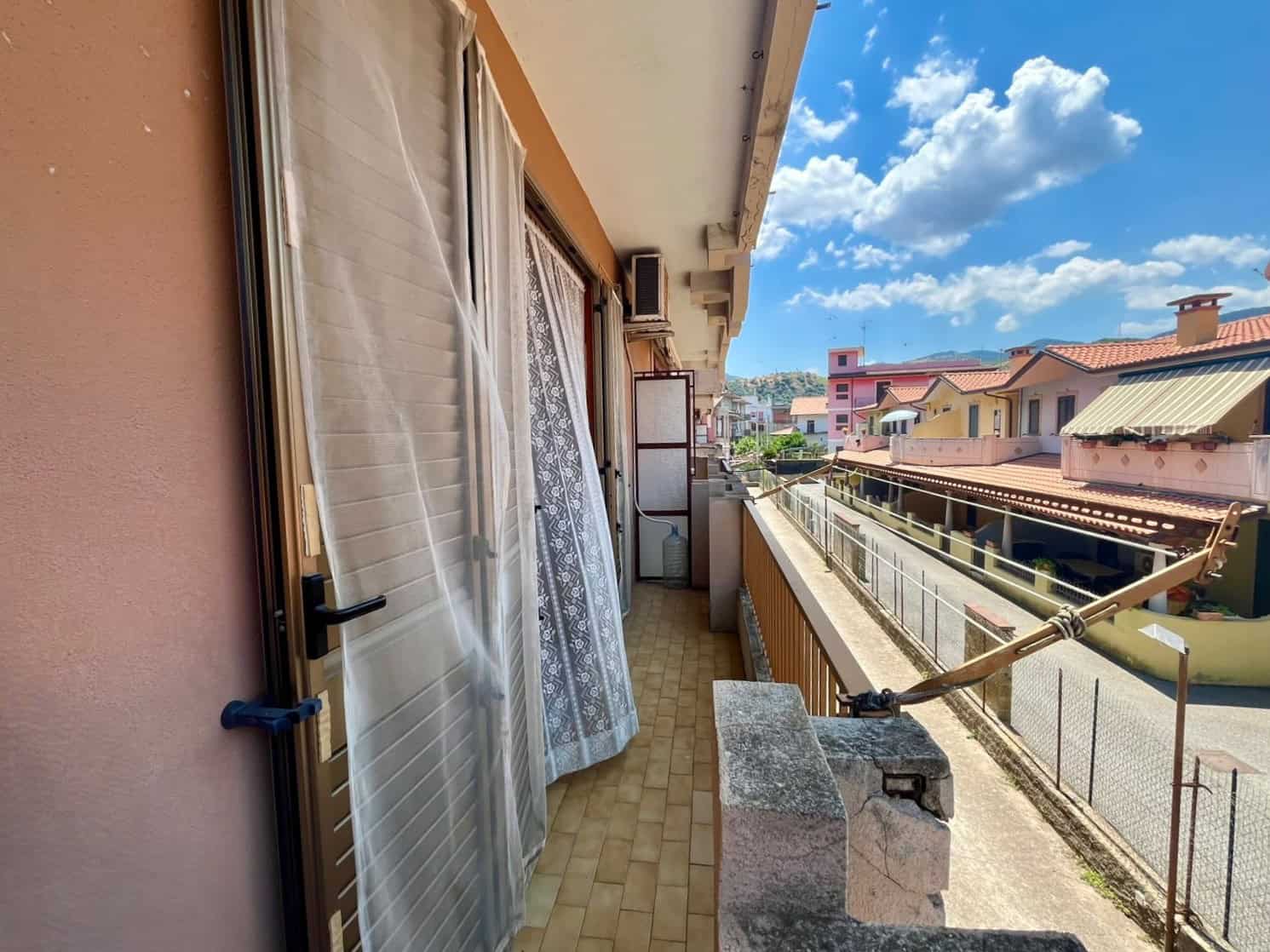 Balcone di un appartamento in vendita a Oliveri con vista su case e cielo sereno.