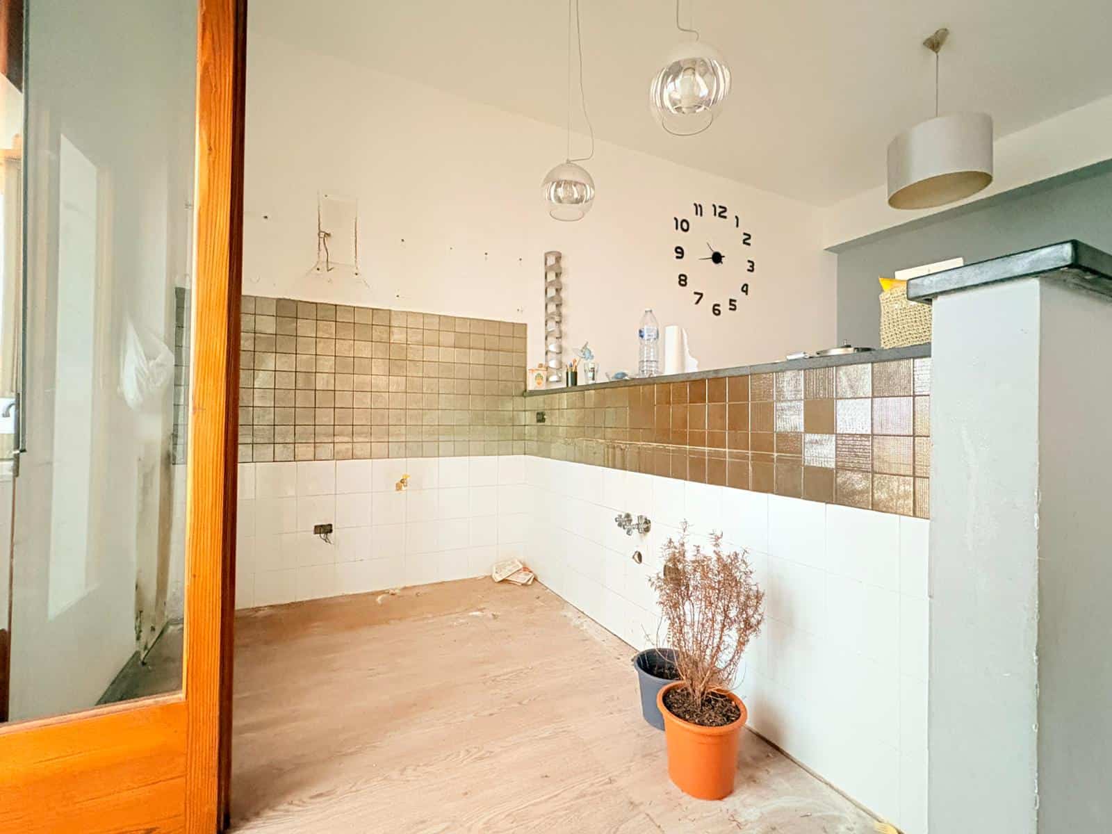 Interno di un appartamento in affitto a Milazzo con pareti bianche, piastrelle marroni e decorazioni minimaliste.