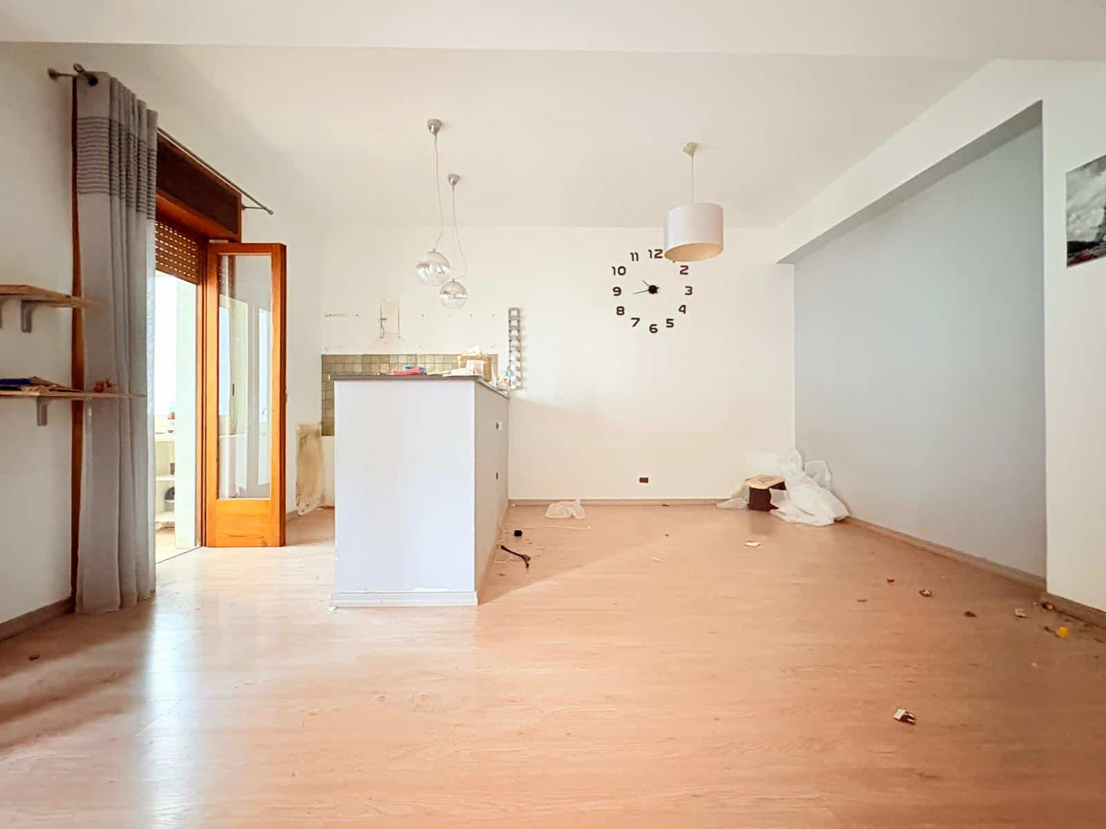 Interno vuoto di un appartamento in affitto a Milazzo con pareti bianche e pavimento in legno chiaro.