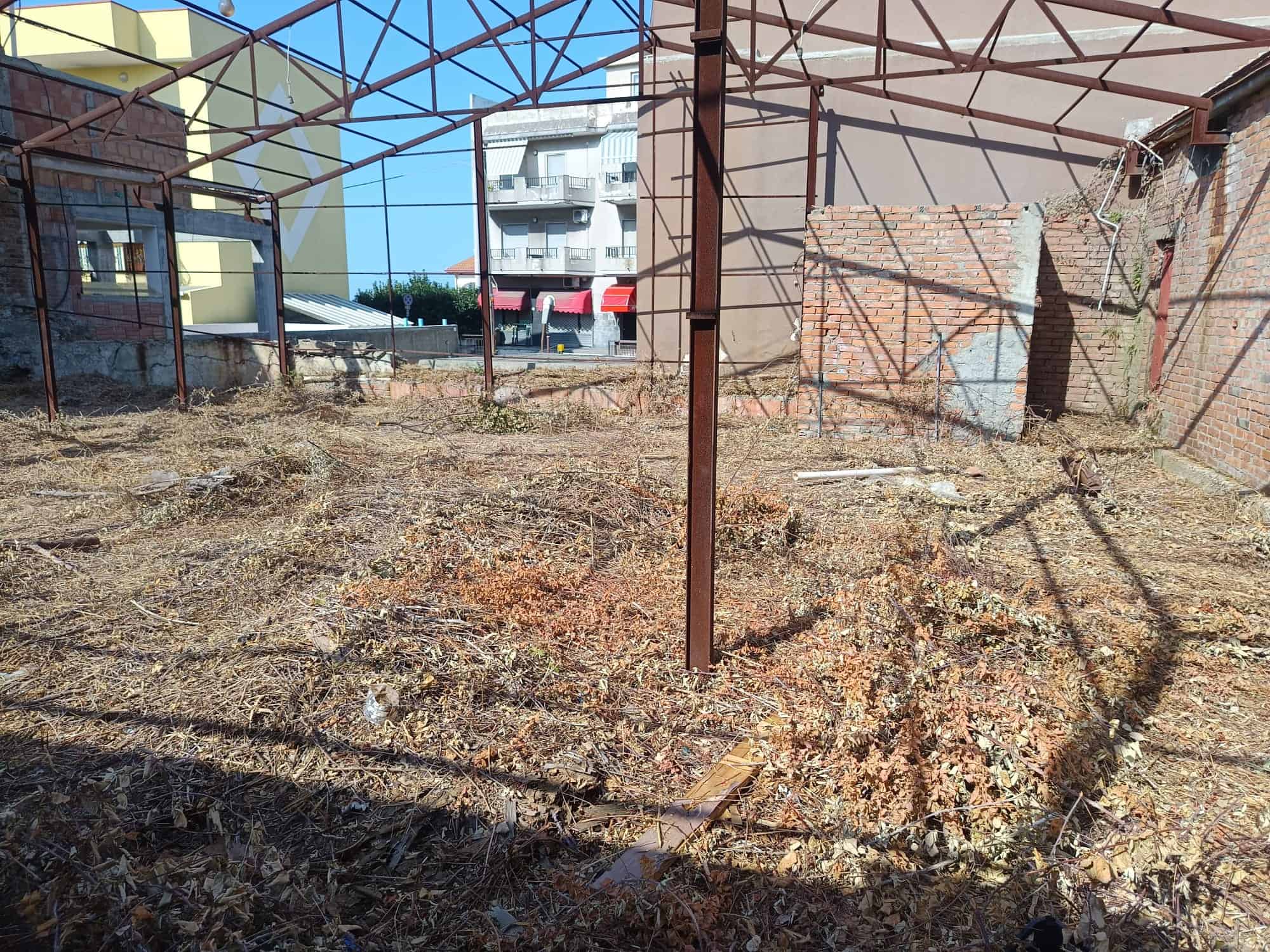 Terreno agricolo all'aperto con struttura metallica e recinzione in mattoni a Villafranca Tirrena, ME.