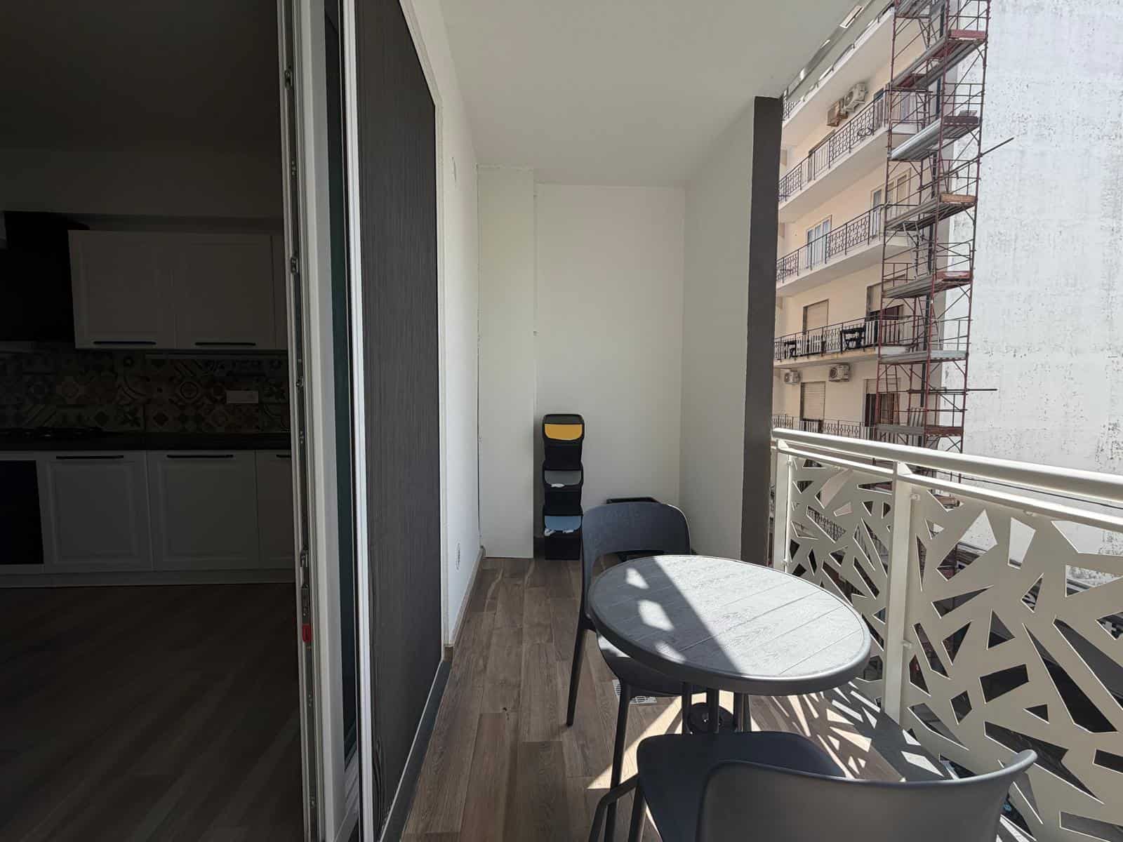 Balcone di un appartamento in vendita a Milazzo con vista su edifici circostanti, arredato con tavolo e sedie, ideale per relax e momenti all'aperto.