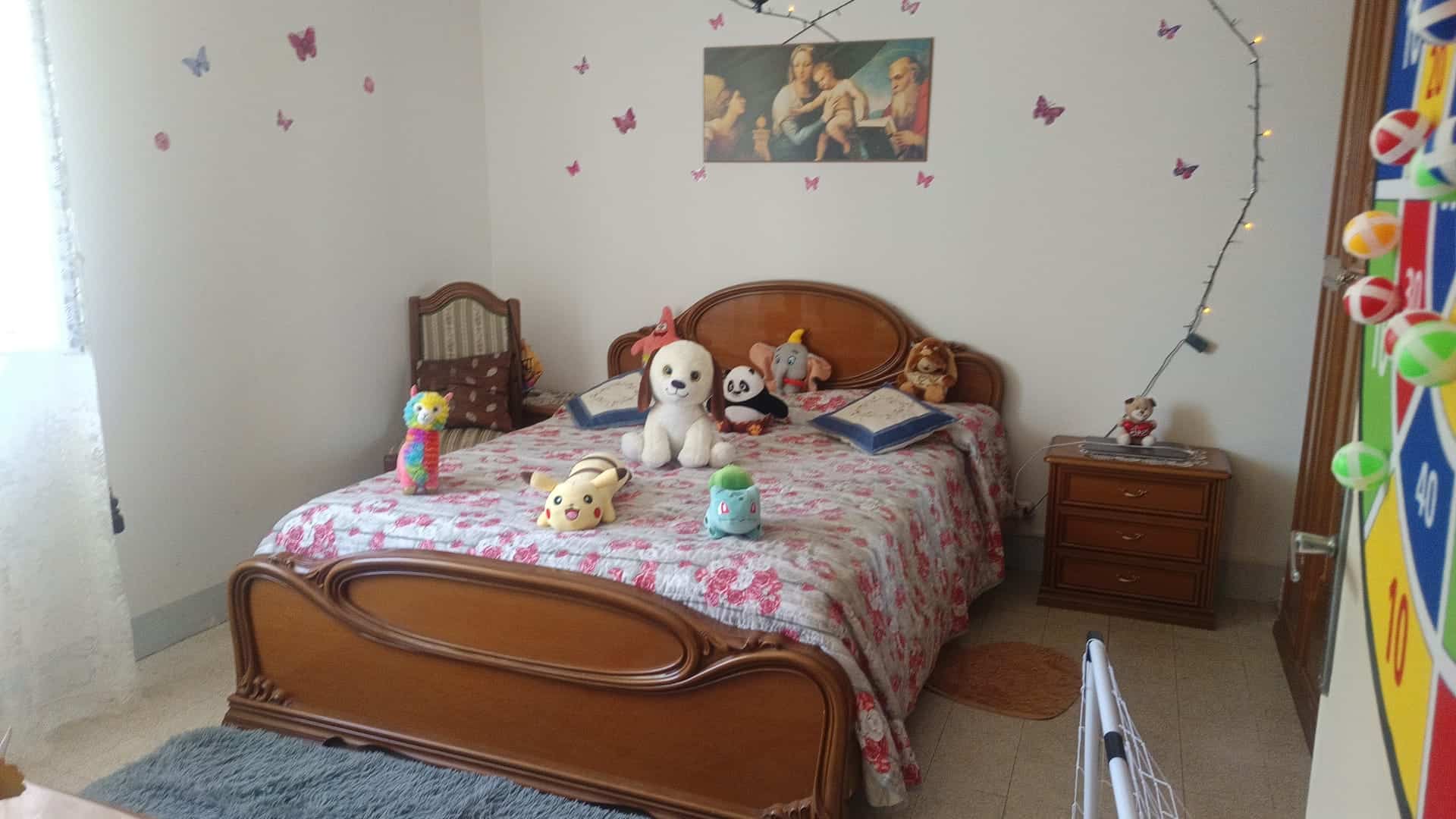 Camera che mostra una camera da letto con letto matrimoniale, decorazioni e giocattoli, in un appartamento in vendita a Rometta, ME.