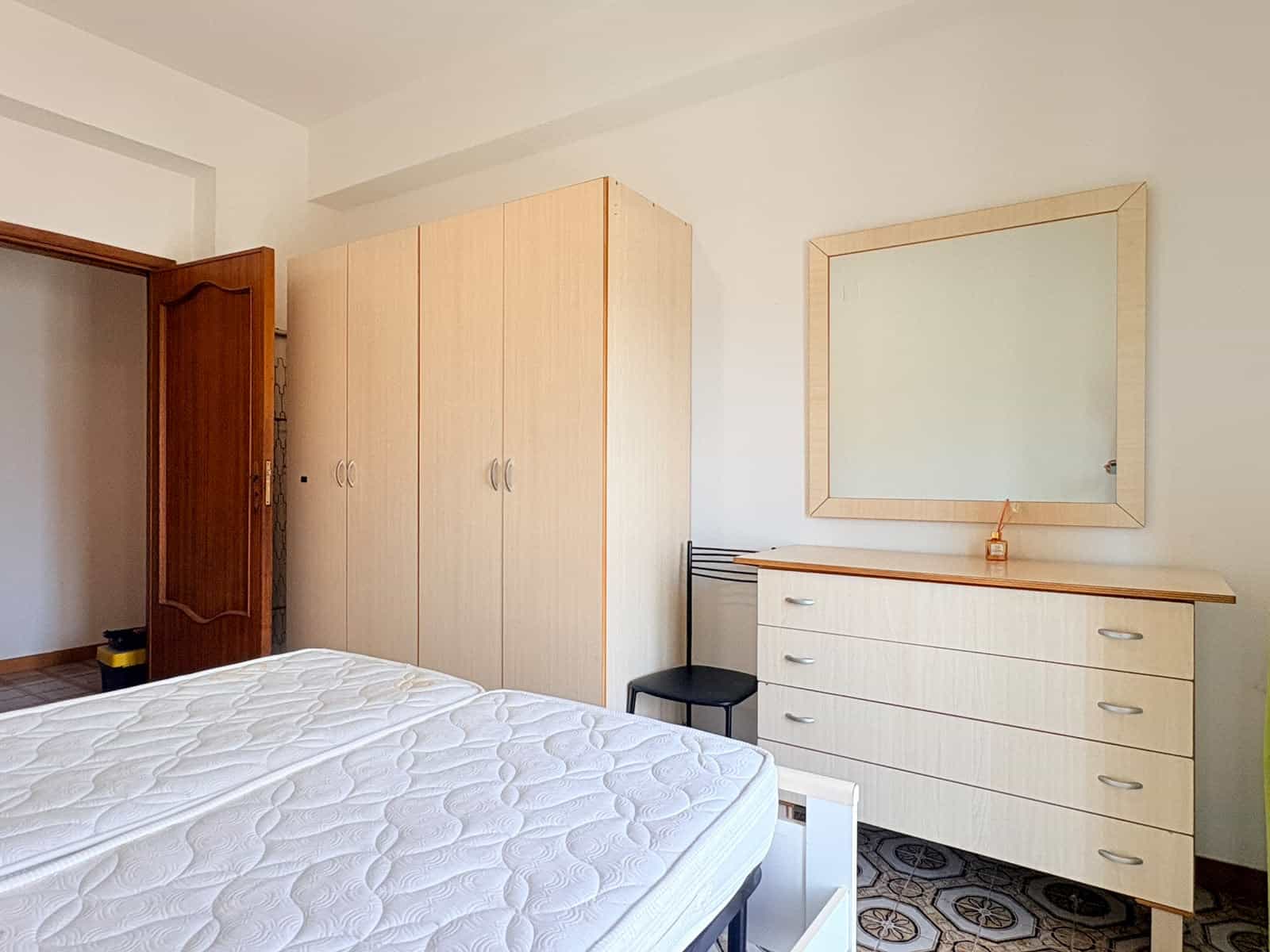 Camera da letto moderna con armadio, comò e specchio in un appartamento in affitto a Milazzo.