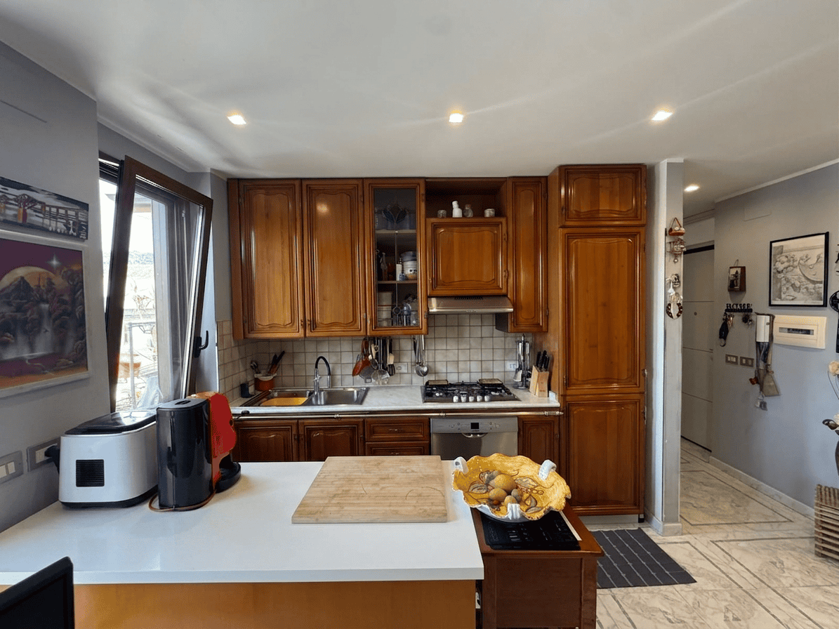 Cucina moderna con mobili in legno, elettrodomestici e spazio ben organizzato, ideale per la vita quotidiana e la preparazione dei pasti.