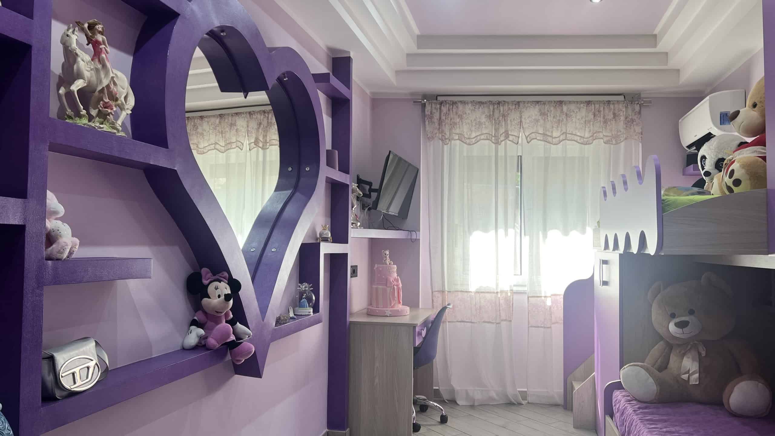 Interno di una camera da letto moderna con pareti viola, letti con teddy bear e decorazioni colorate, luminosa grazie a una finestra grande con tende leggere.