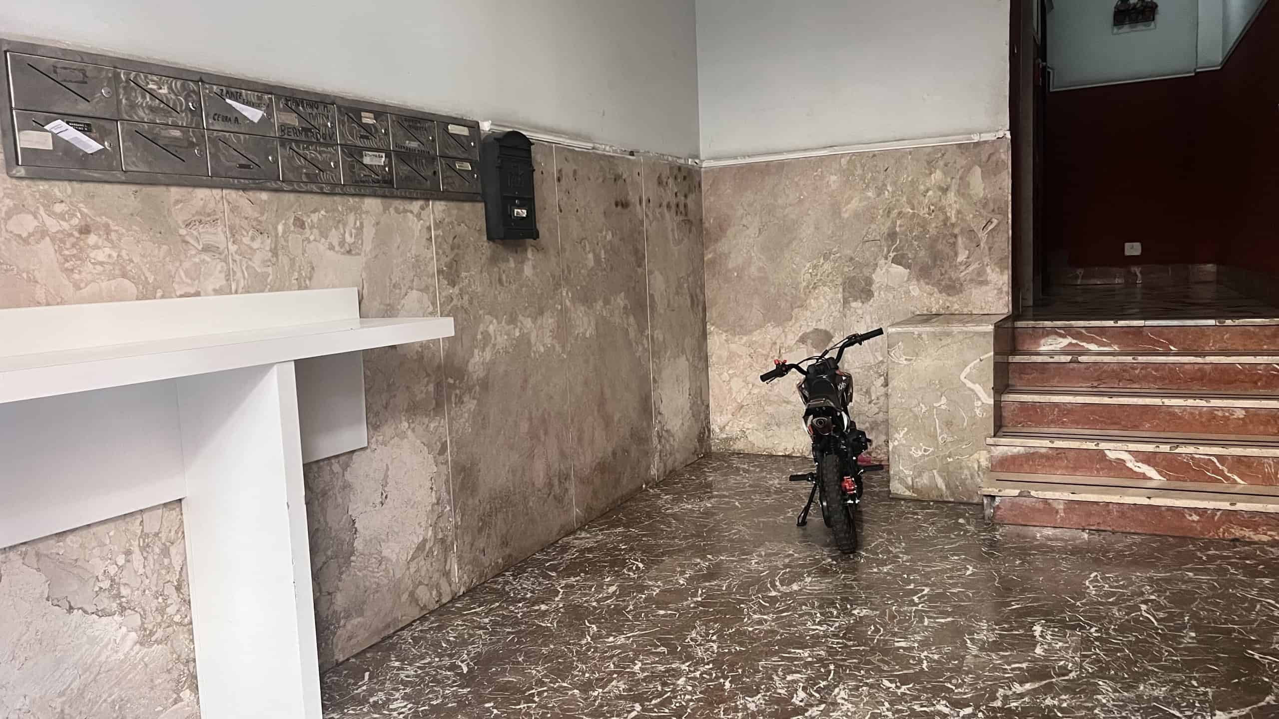 Ingresso condominiale con bici e scale in marmo, ingresso di un appartamento in vendita a Messina.