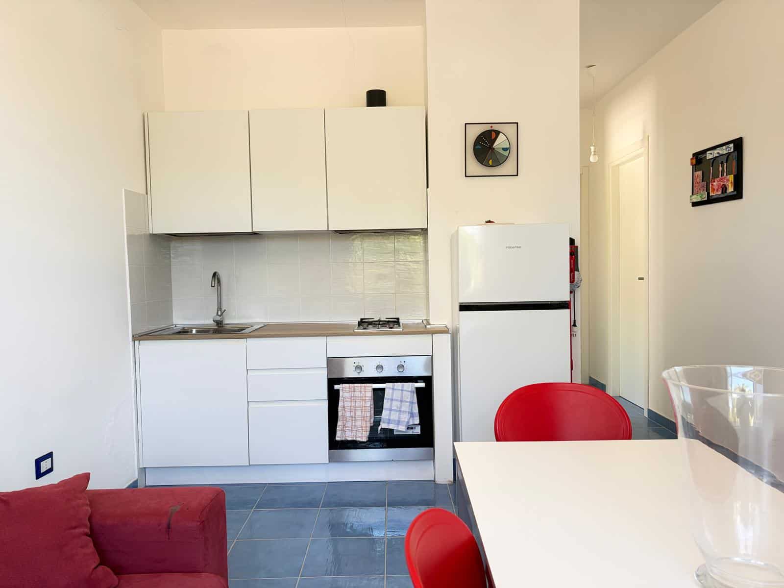 Cucina compatta e moderna con elettrodomestici bianchi e pareti chiare, ideale per appartamenti NextCasa.