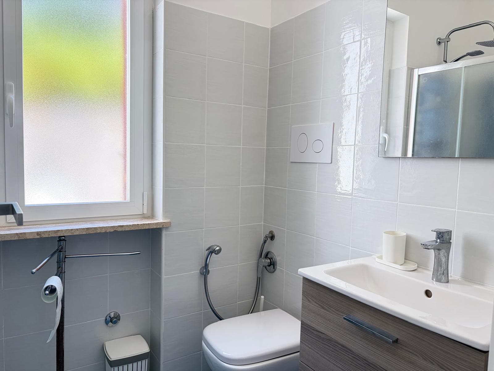 Bagno con sanitari moderni, finestra e specchio, ambiente luminoso e pulito.