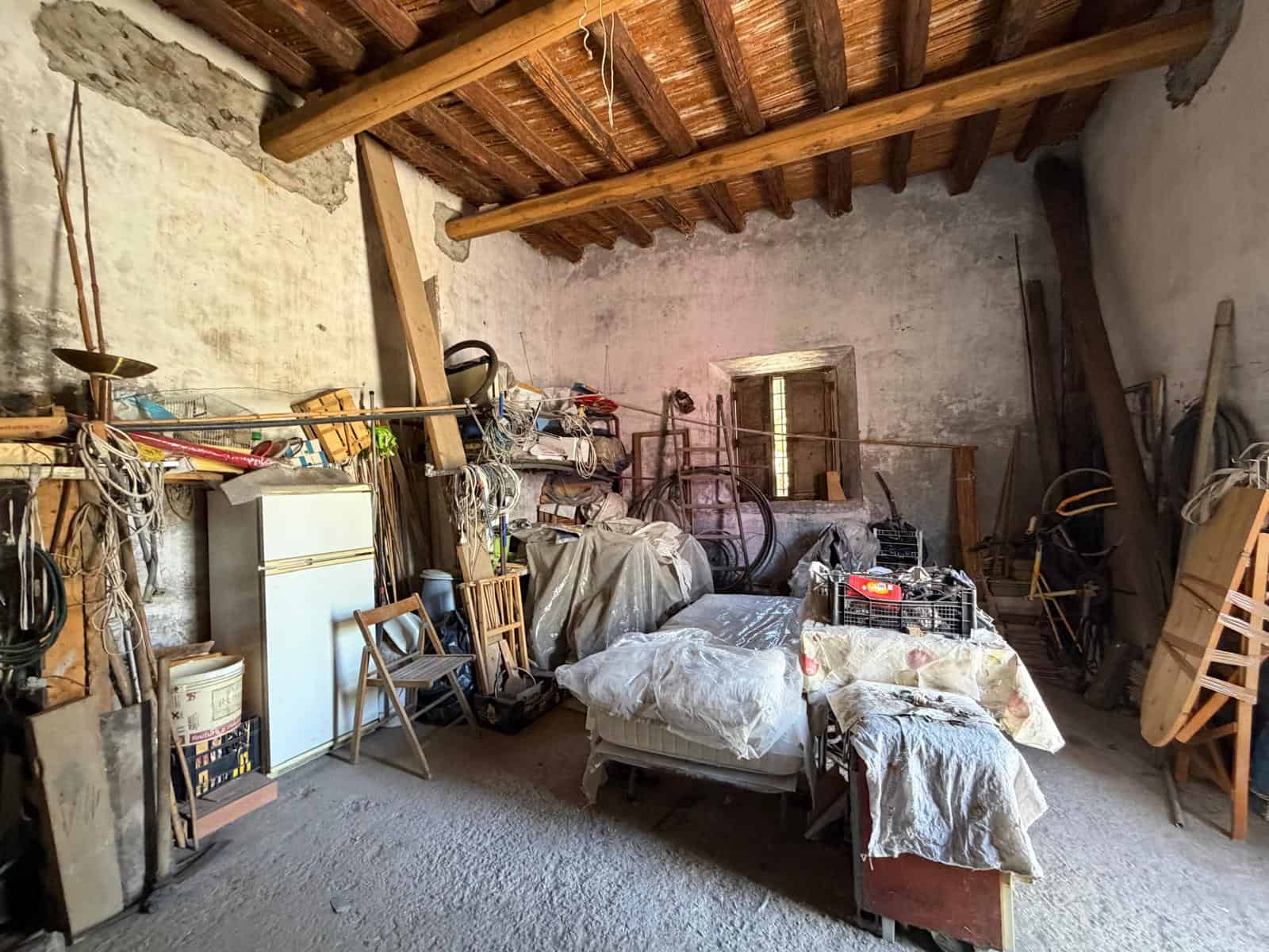 Interno di un rustico con soffitto in legno e mobili vecchi, ideale per ristrutturazione e investimento immobiliare a NextCasa.