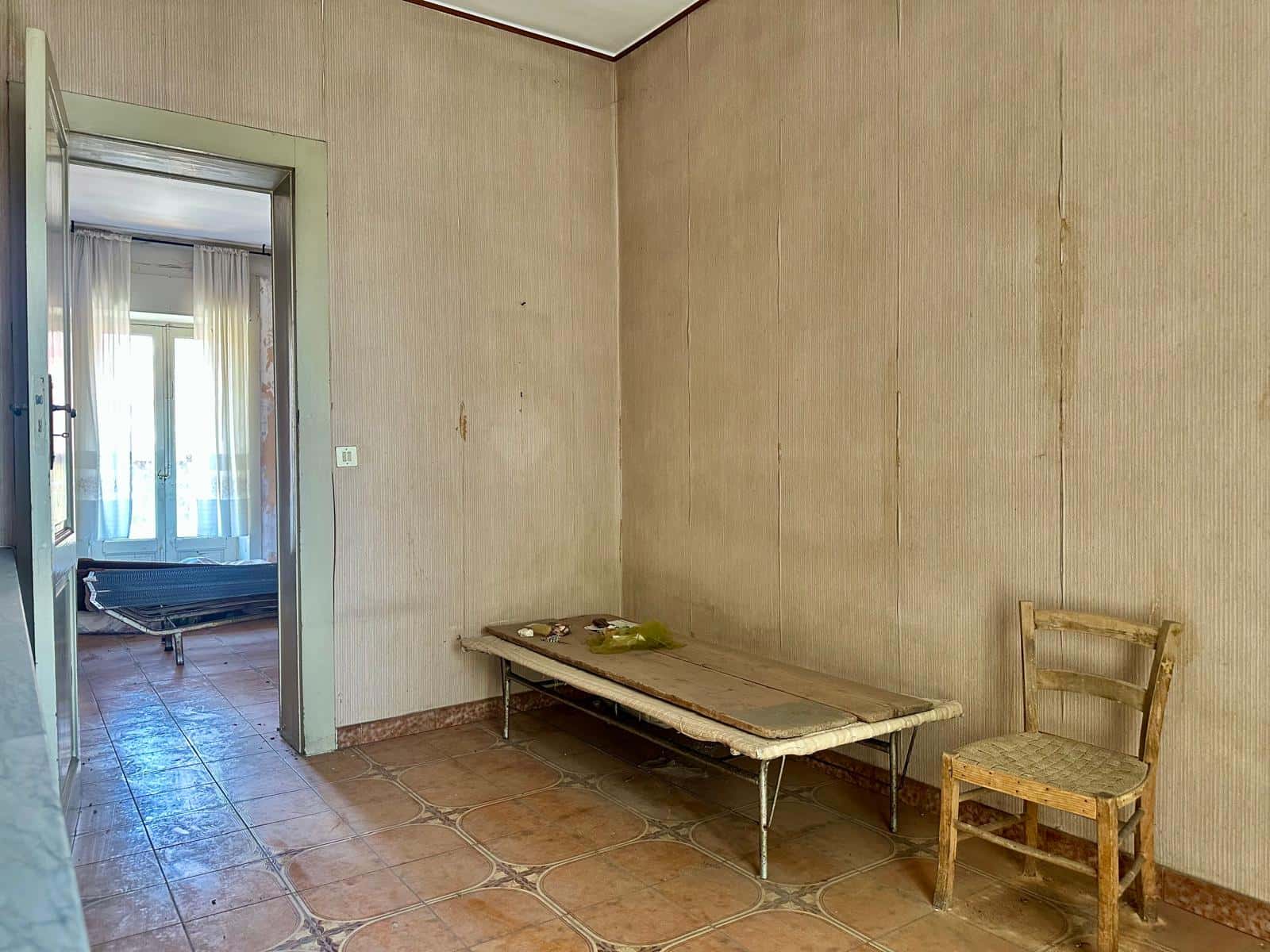 Interno di una casa indipendente in vendita a Barcellona P.G., stanza con pareti beige, pavimento in piastrelle e mobili semplici.