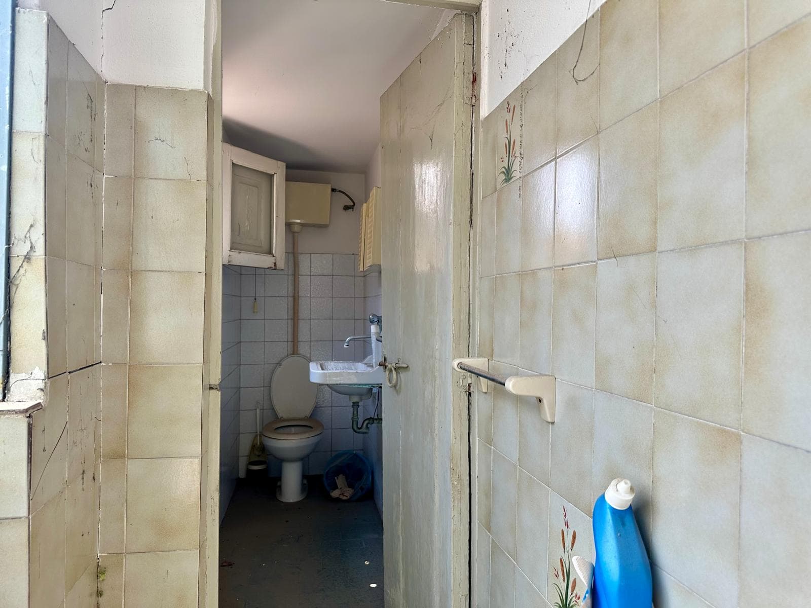 Bagno di servizio con piastrelle beige, lavabo e WC in una casa in vendita a Barcellona P.G.