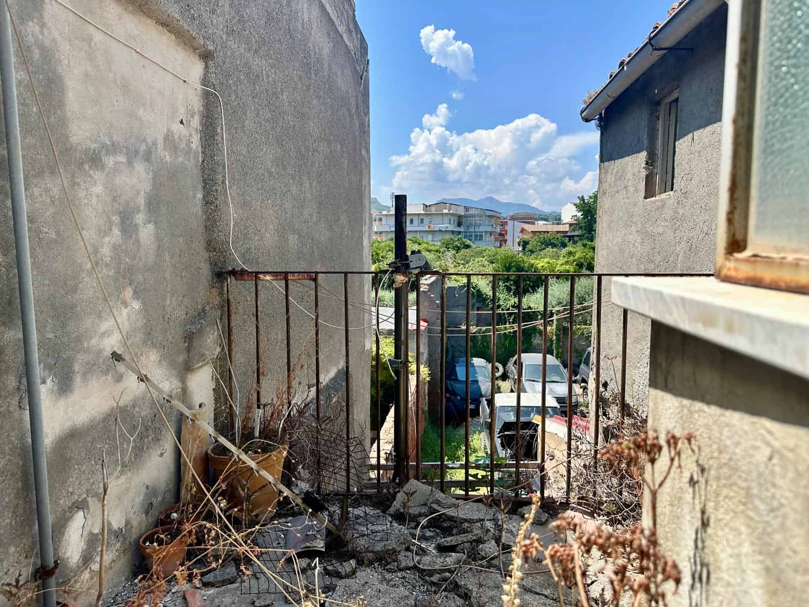 Vista di un cortile con recinzione in ferro e edifici circostanti, in zona urbana di Barcellona P.G.