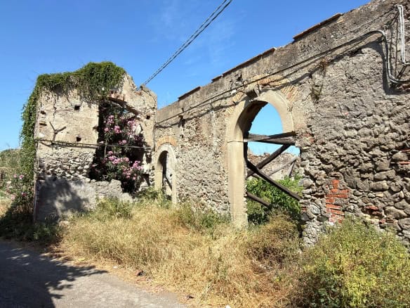 Resti di un edificio storico in pietra con archi e vegetazione, scenario rurale in Italia.