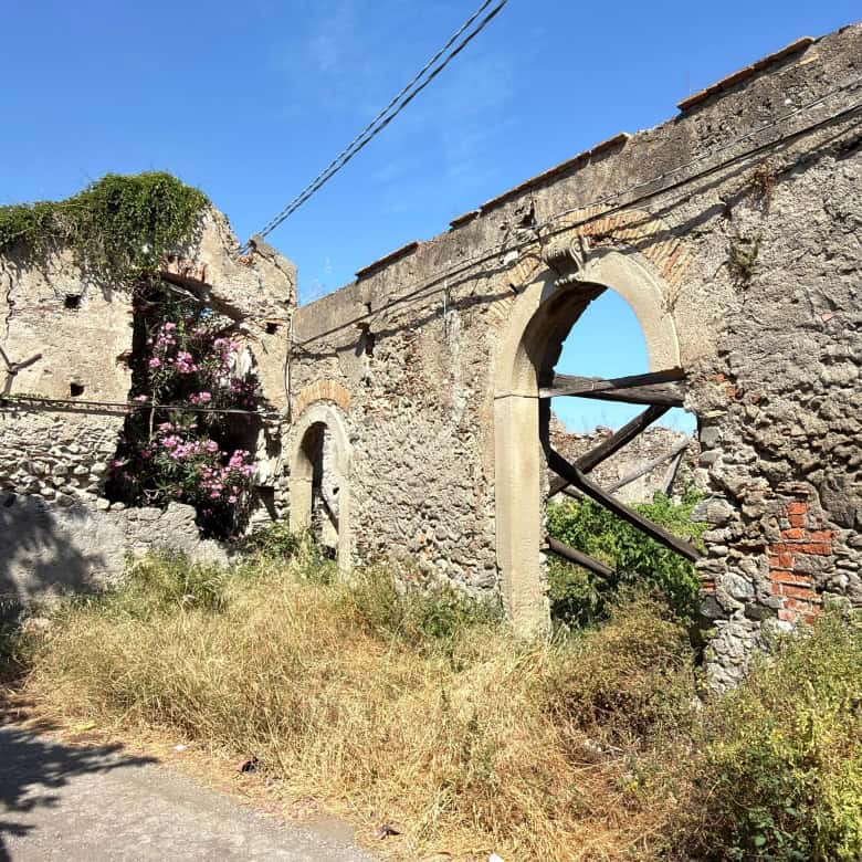 Resti di un edificio storico in pietra con archi e vegetazione, scenario rurale in Italia.