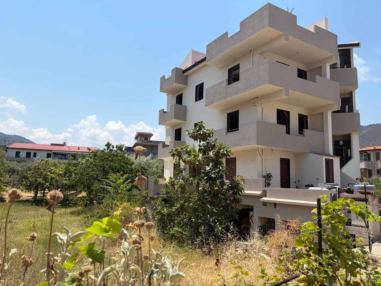 Appartamento in vendita a Oliveri, edificio moderno con balconi e giardino circostante.