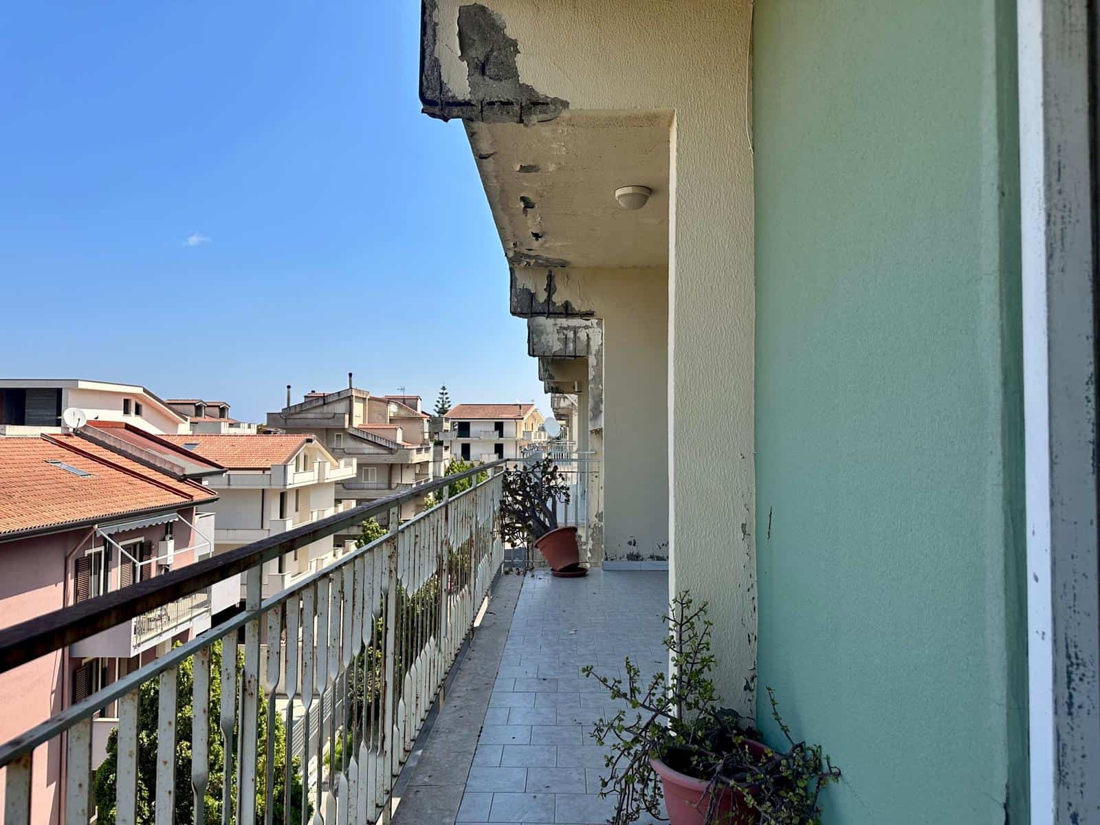 Balcone di un appartamento con vista sulla città, con piante in vaso e ringhiera in ferro, in un edificio in via Delle Ginestre.