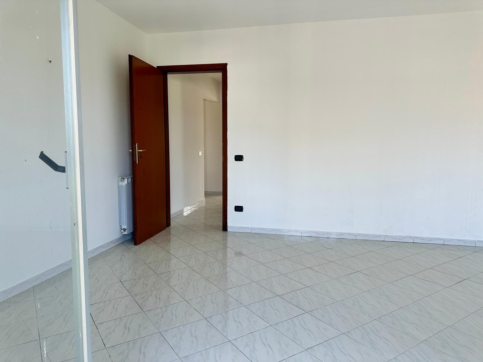 Interno di un appartamento in vendita in via Delle Ginestre, stanza luminosa con pareti bianche e pavimento in piastrelle.