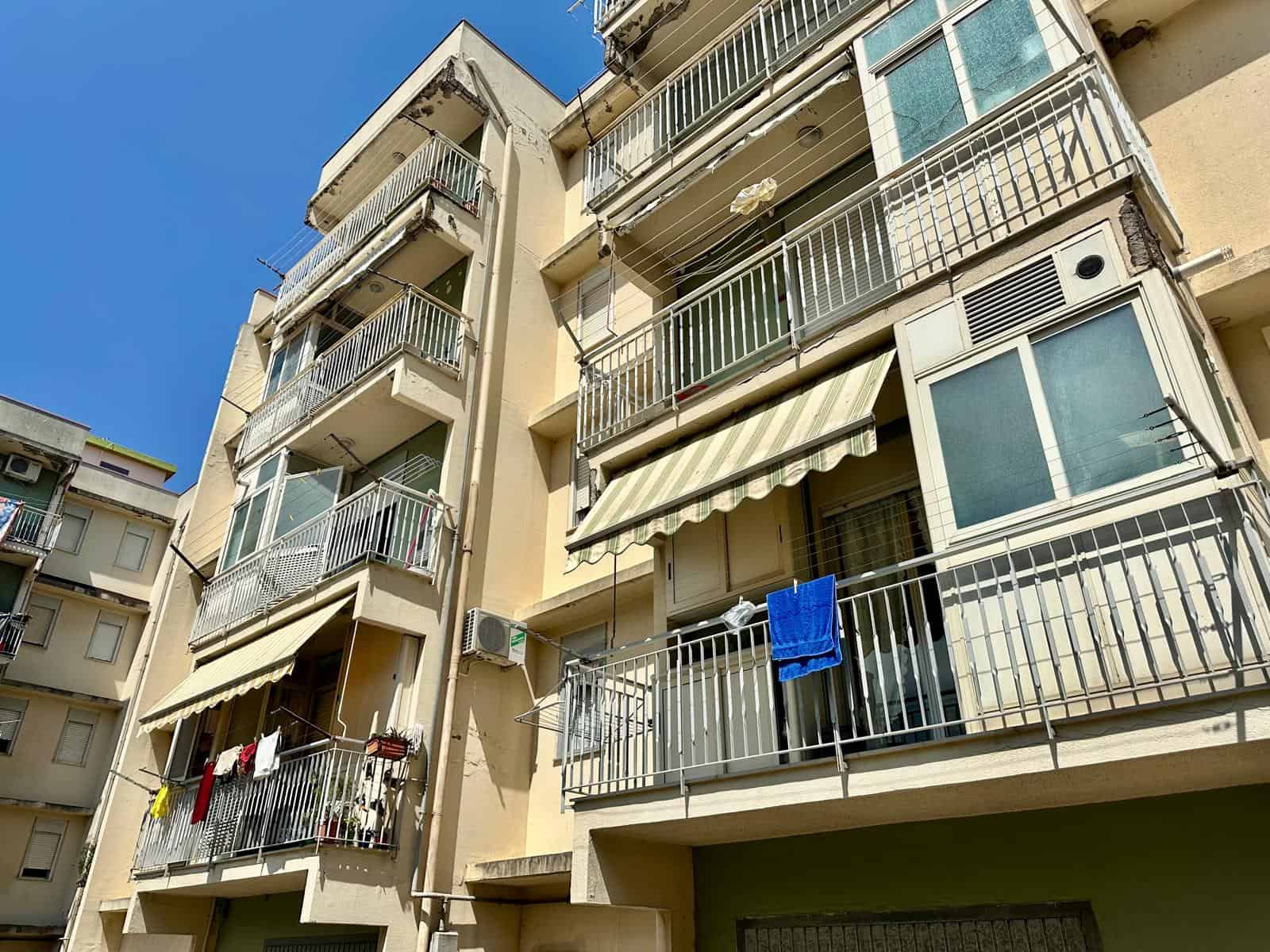 Facciata di un edificio residenziale con balconi e tende parasole, in zona urbana.