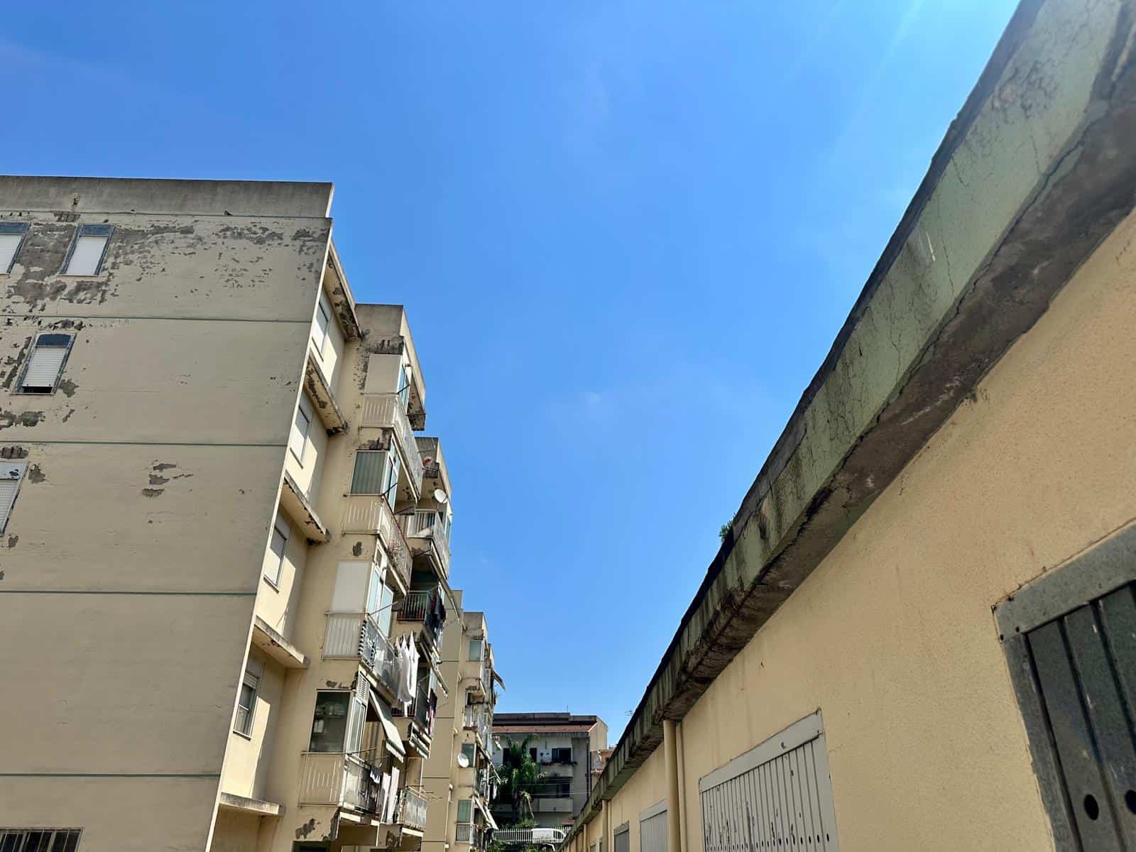 Vista di un complesso residenziale in via Delle Ginestre con edifici alti e balconi sotto un cielo azzurro.