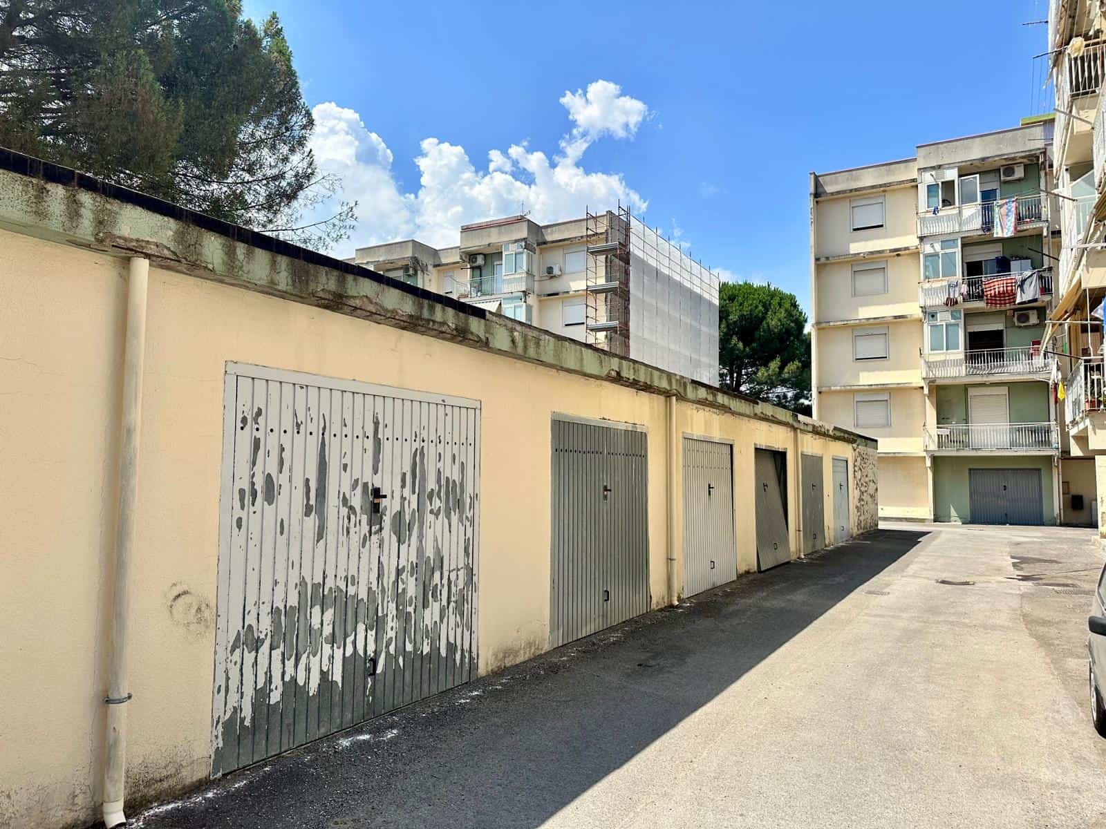 Garage e parcheggi in un complesso residenziale in via Delle Ginestre, con edifici moderni sullo sfondo.