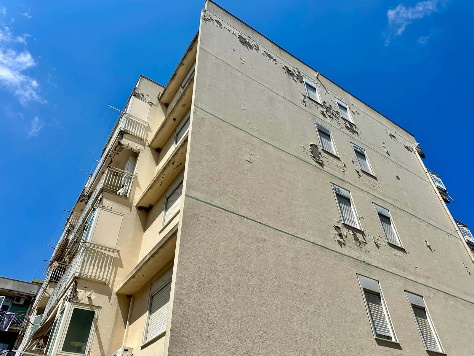 Edificio residenziale in vendita in via Delle Ginestre con facciata bianca e balconi, sotto un cielo azzurro.