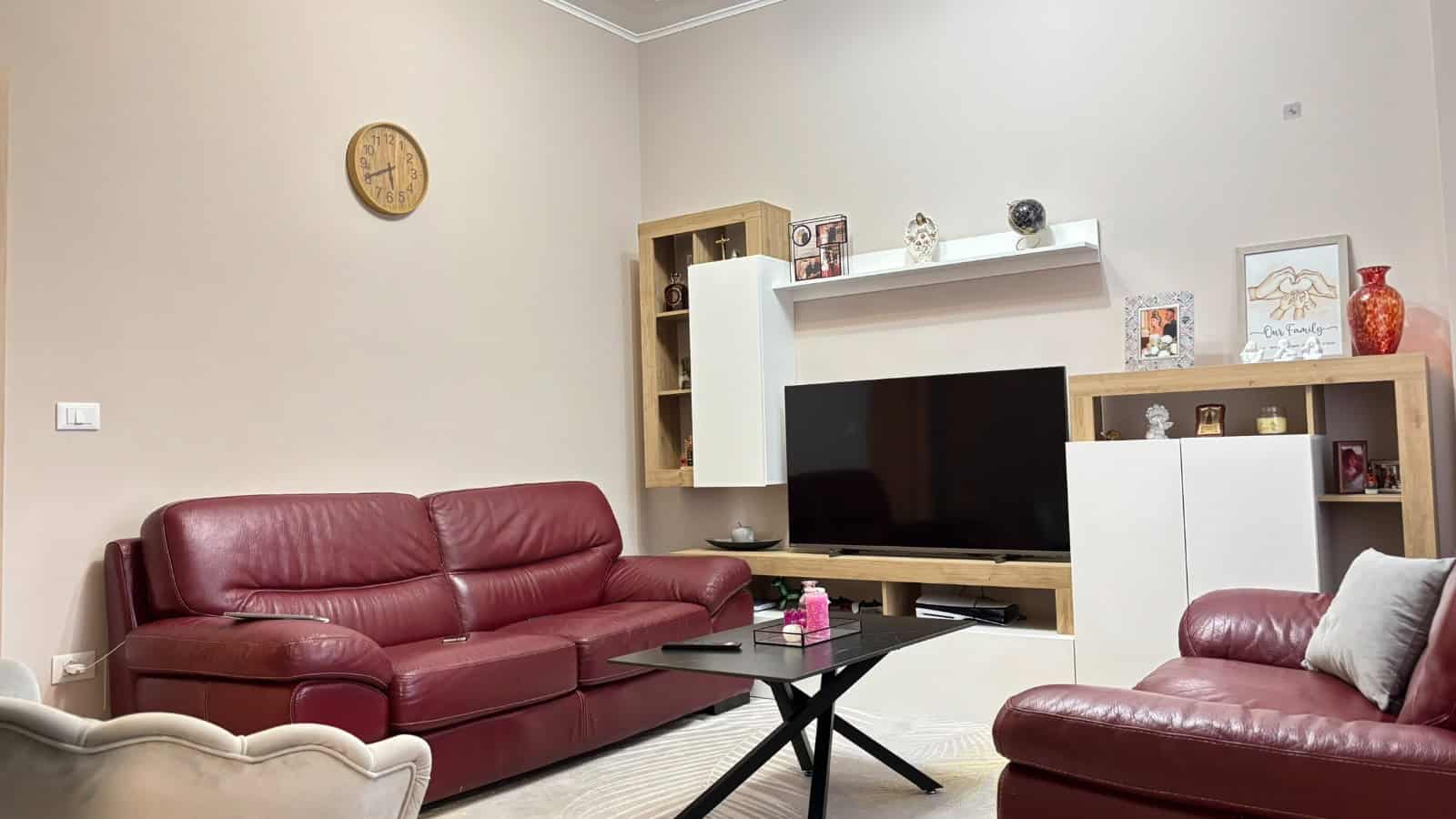Interno soggiorno con divani in pelle rossa, TV e arredi moderni in un appartamento a Milazzo.