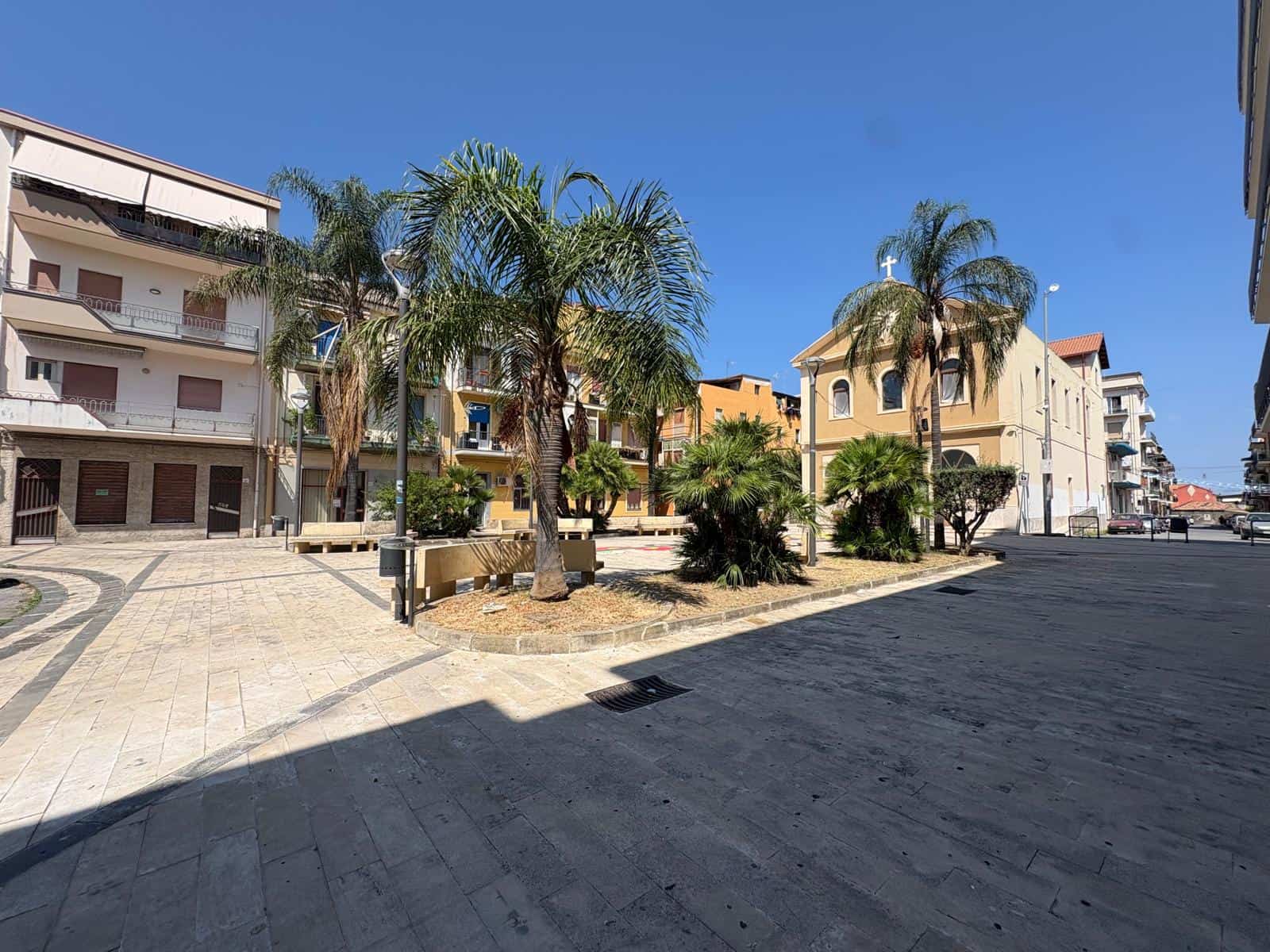Piazza con palme e chiesa in stile classico a Barcellona P.G., Sicilia, Italia.