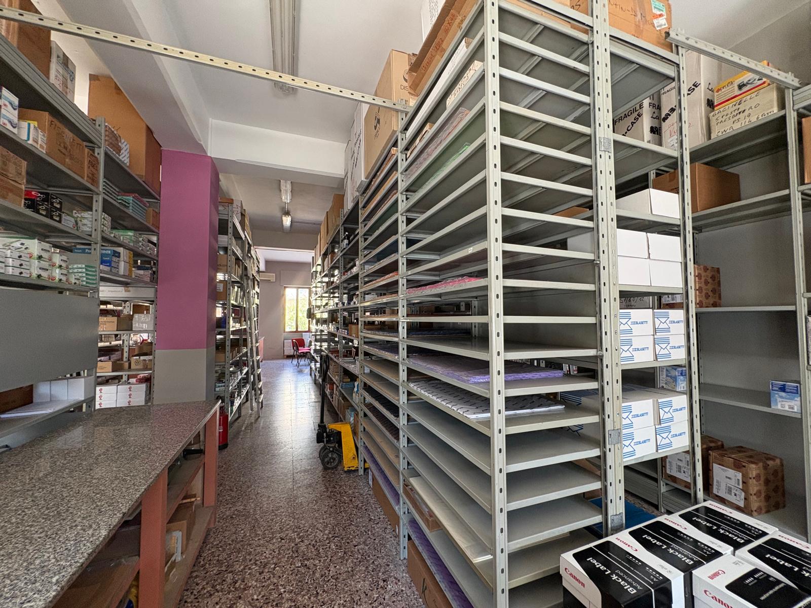 Scaffalature metalliche in un magazzino con scatole e materiali vari, spazio ben organizzato.