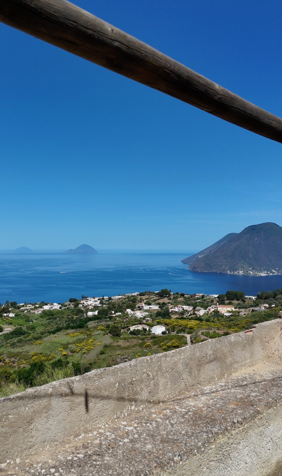 Vista panoramica di Lipari con mare, isole e paesaggio collinare sotto un cielo sereno.