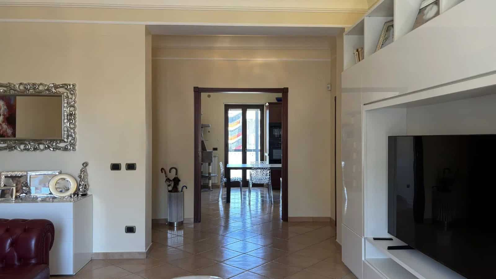 Interno di un appartamento in vendita a Milazzo, vista sul soggiorno con porta finestra e arredamento moderno.