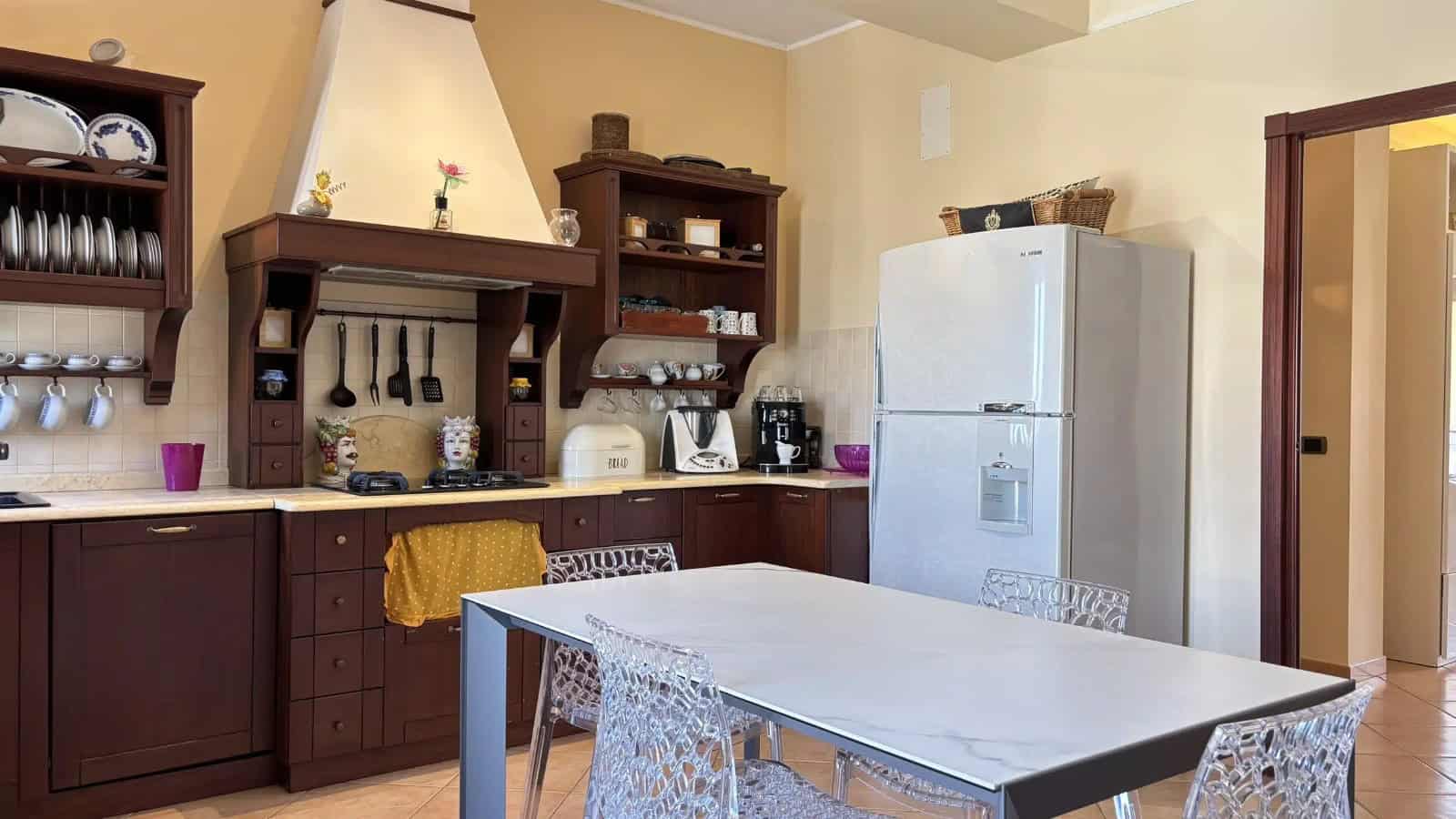 Interno di un appartamento con cucina moderna e zona pranzo, dettagli di arredi in legno e elettrodomestici.