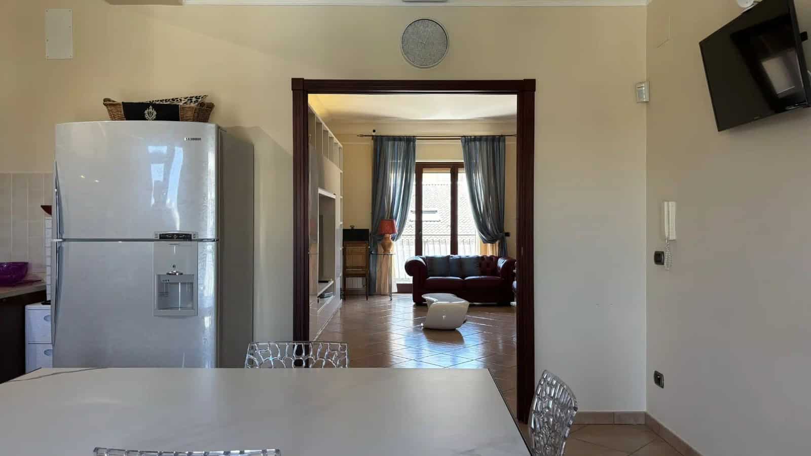 Interno di un appartamento in vendita a Milazzo, vista soggiorno con divano e finestra con tende blu.