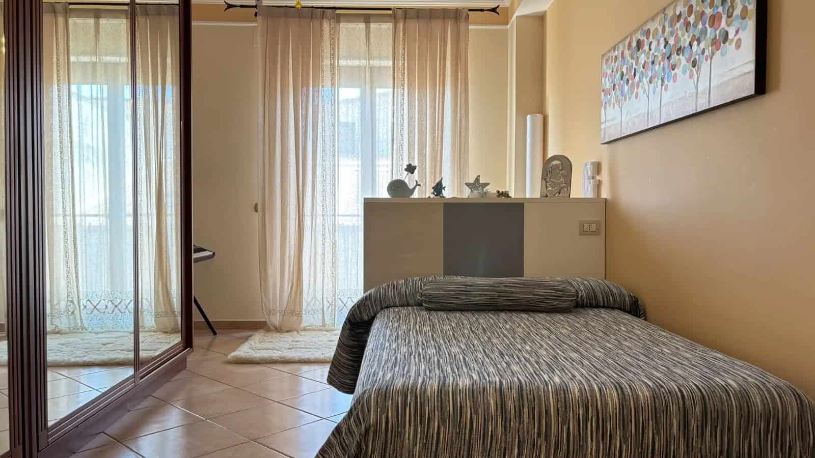 Camera da letto luminosa con grande finestra e arredi moderni in un appartamento a Milazzo.