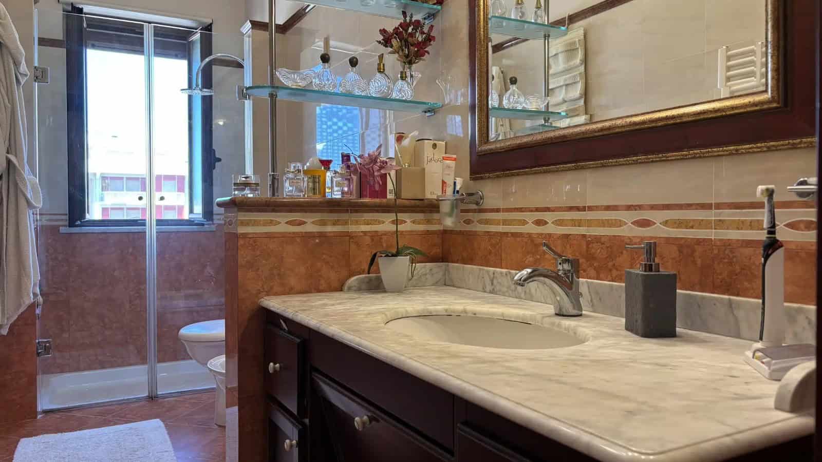 Bagno con lavabo, specchio e doccia in un appartamento in vendita a Milazzo, ME.