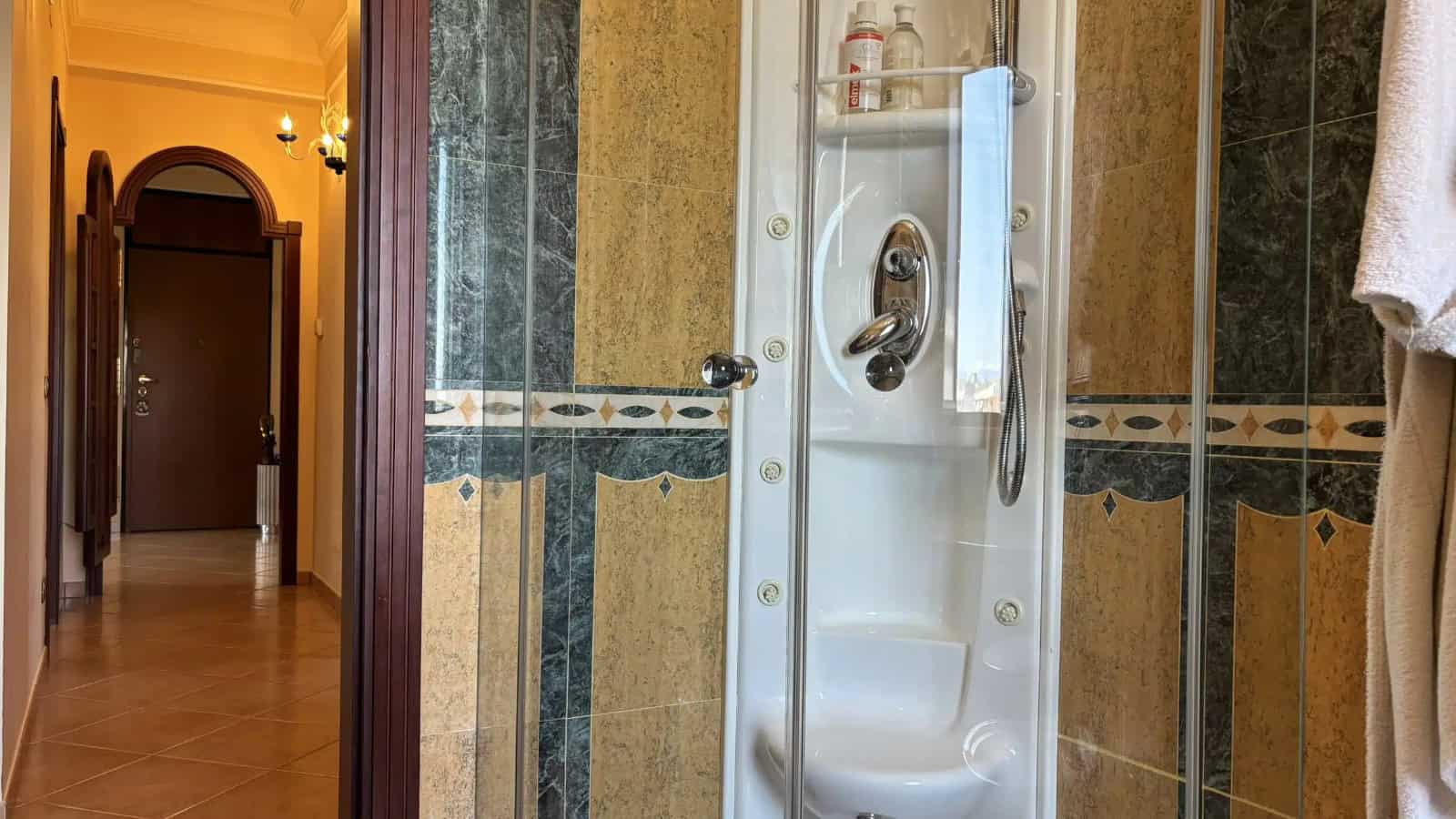 Doccia moderna in bagno con pareti in piastrelle beige e dettagli decorativi.